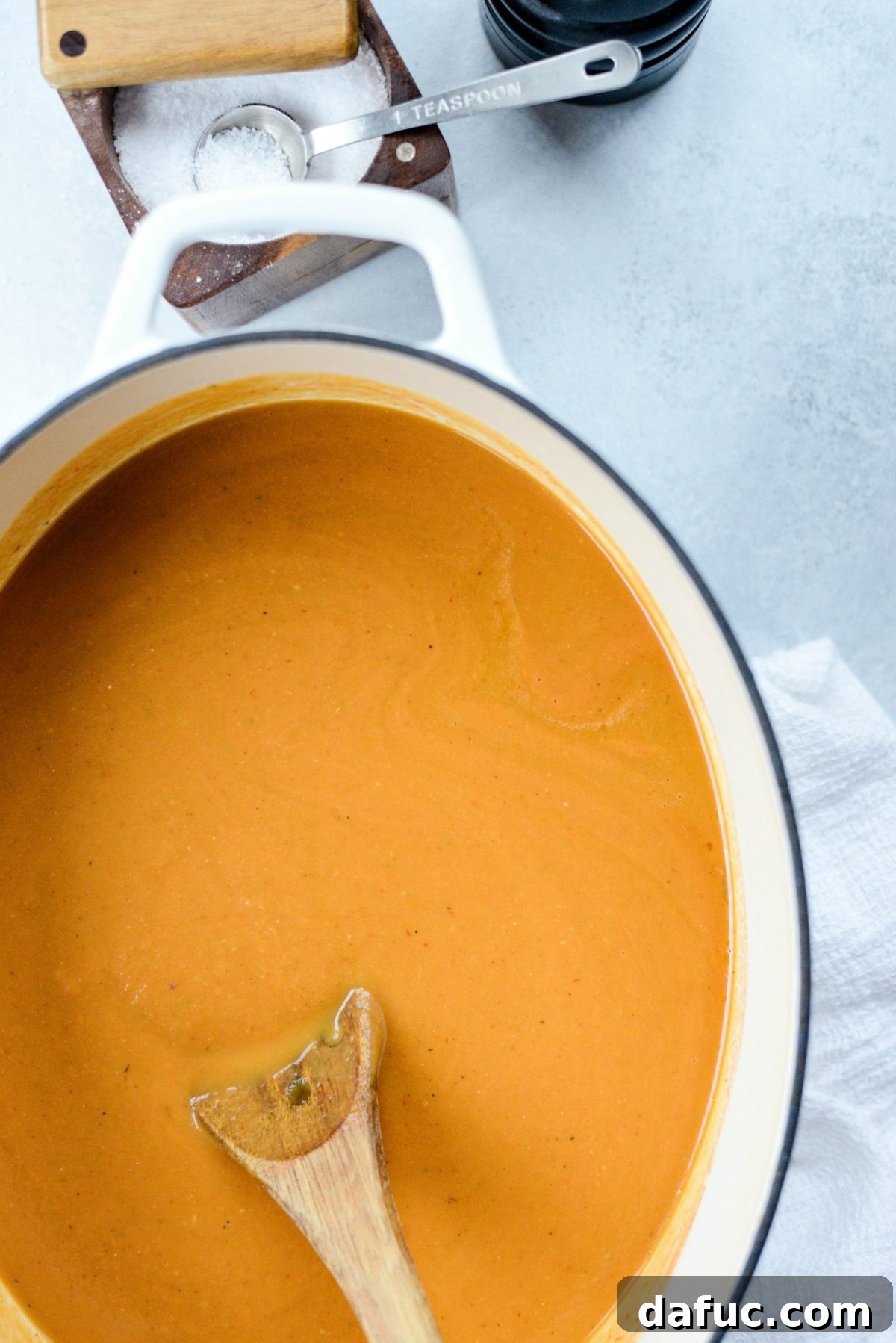 Roasted Tomato Pumpkin Soup being stirred in a Dutch oven as it heats through to a piping hot temperature