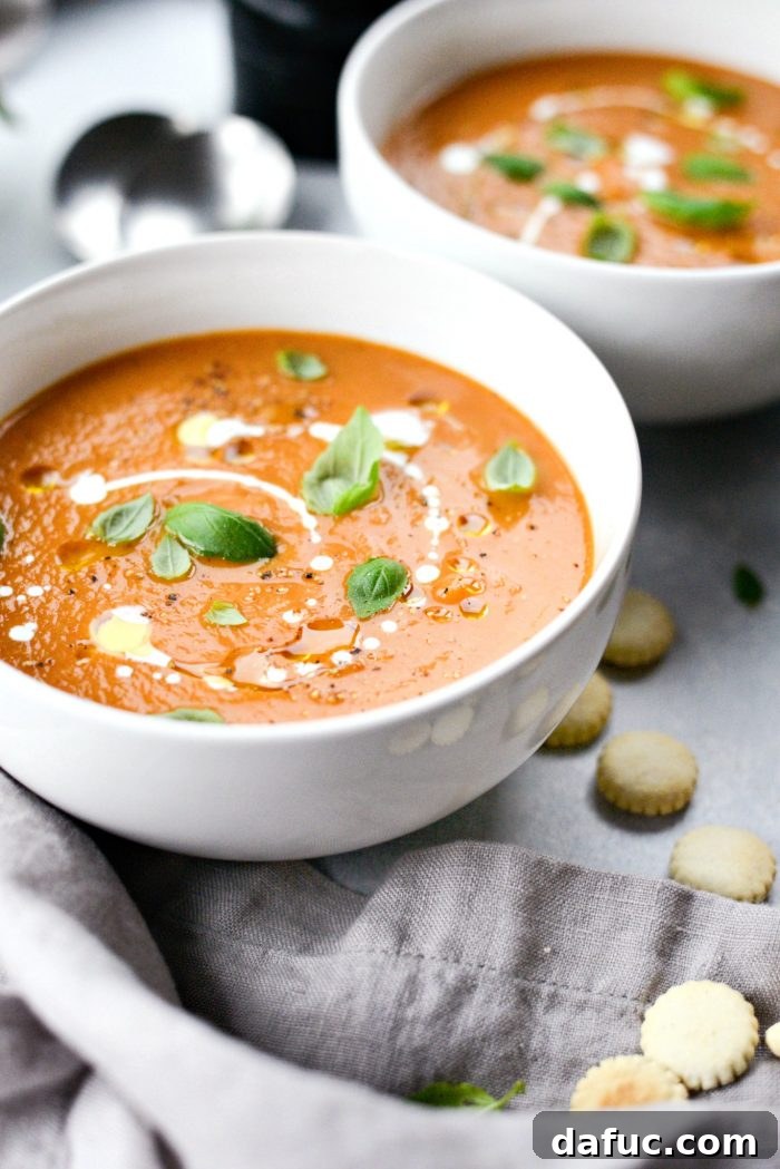 Close-up of a steaming bowl of Roasted Tomato Pumpkin Soup, garnished with fresh herbs and a spoon
