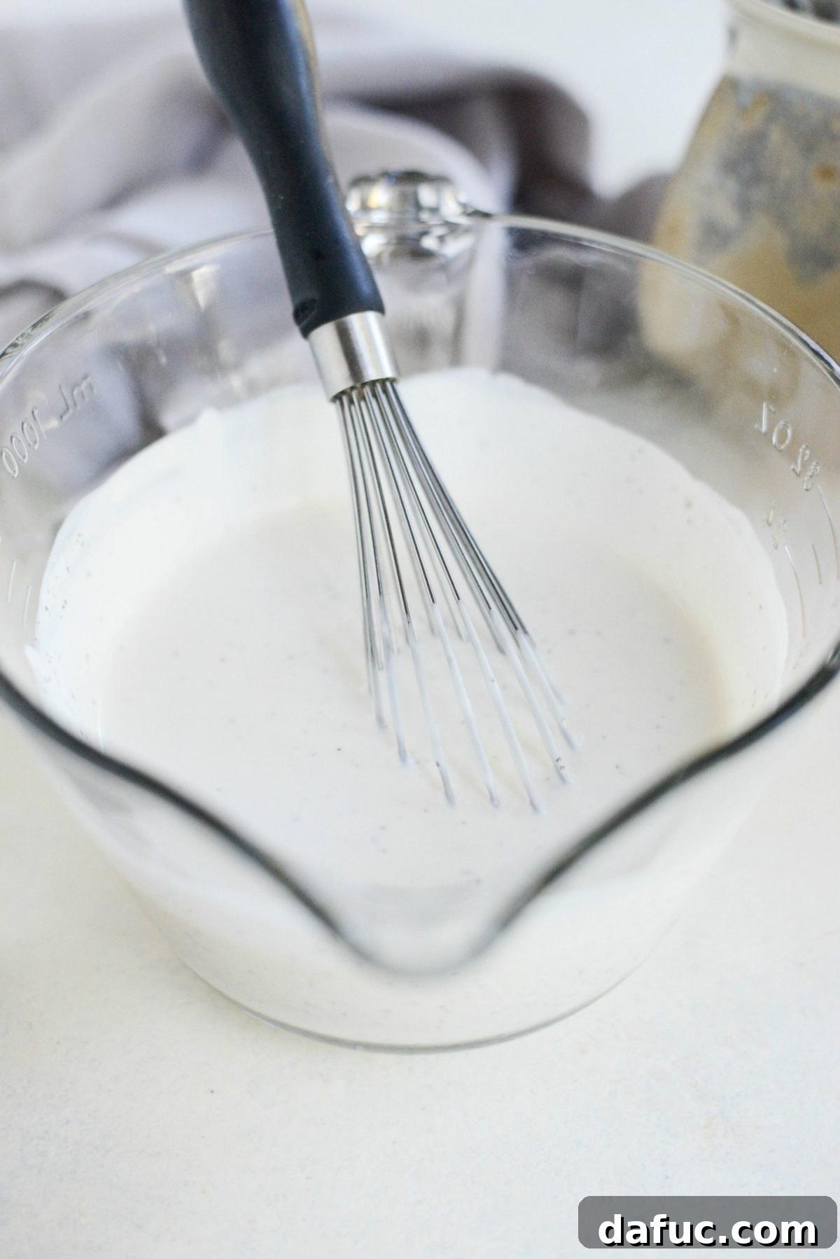 Our Signature Loaded Wedge, Drenched in Peppercorn Buttermilk 5 A bowl of creamy Black Pepper Buttermilk Dressing, ready to be served, showcasing its smooth texture.