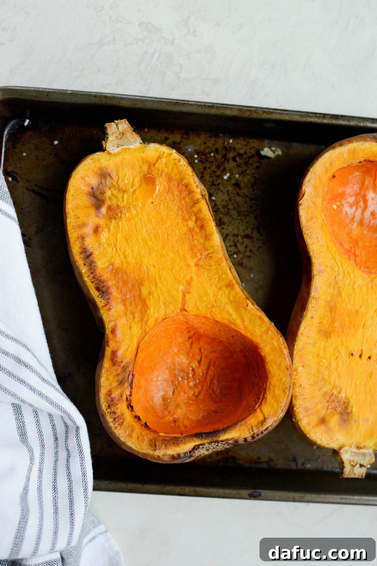 Freshly roasted butternut squash halves on a baking sheet, showcasing their rich color.