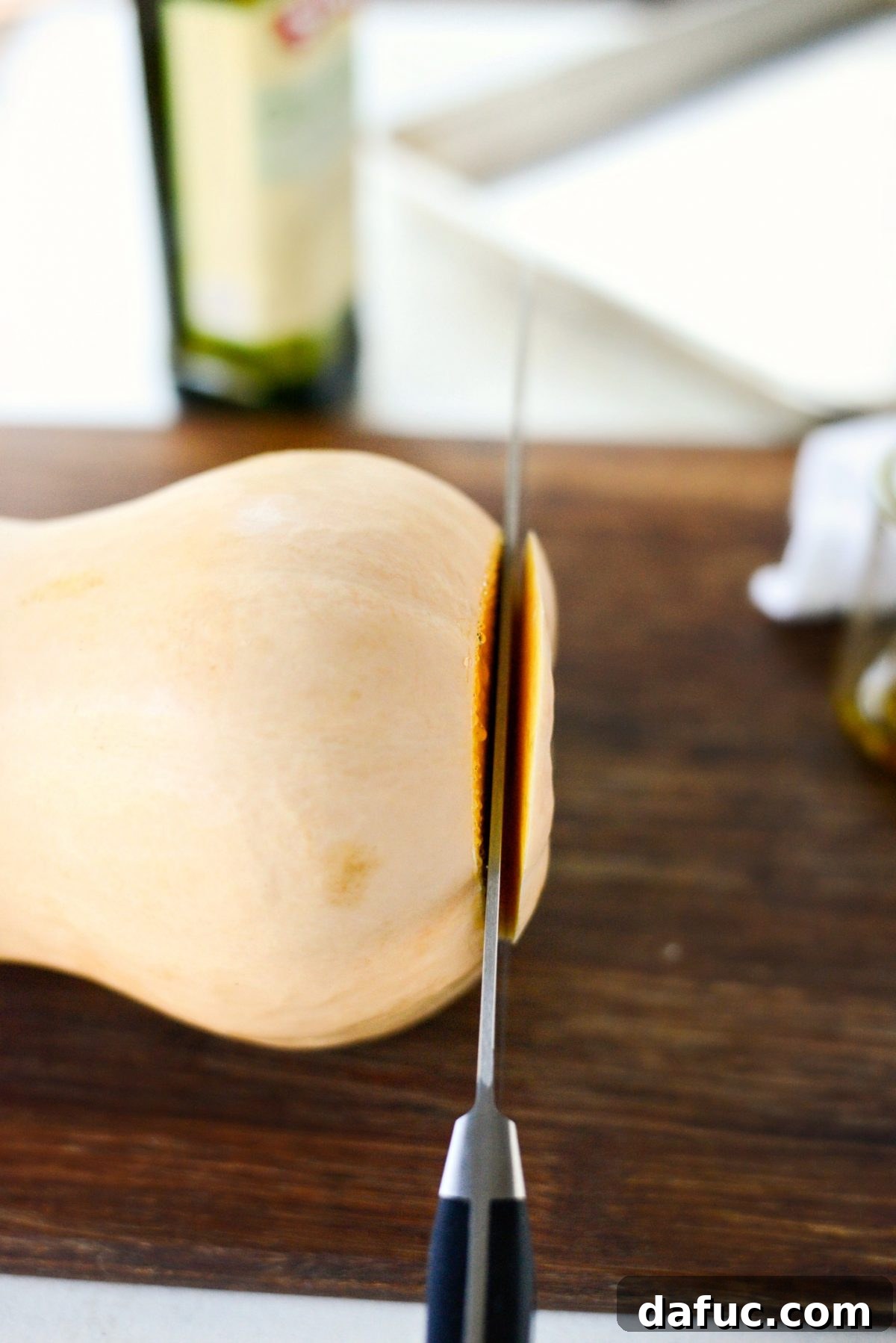 Preparing butternut squash: trimming both ends with a knife on a cutting board.