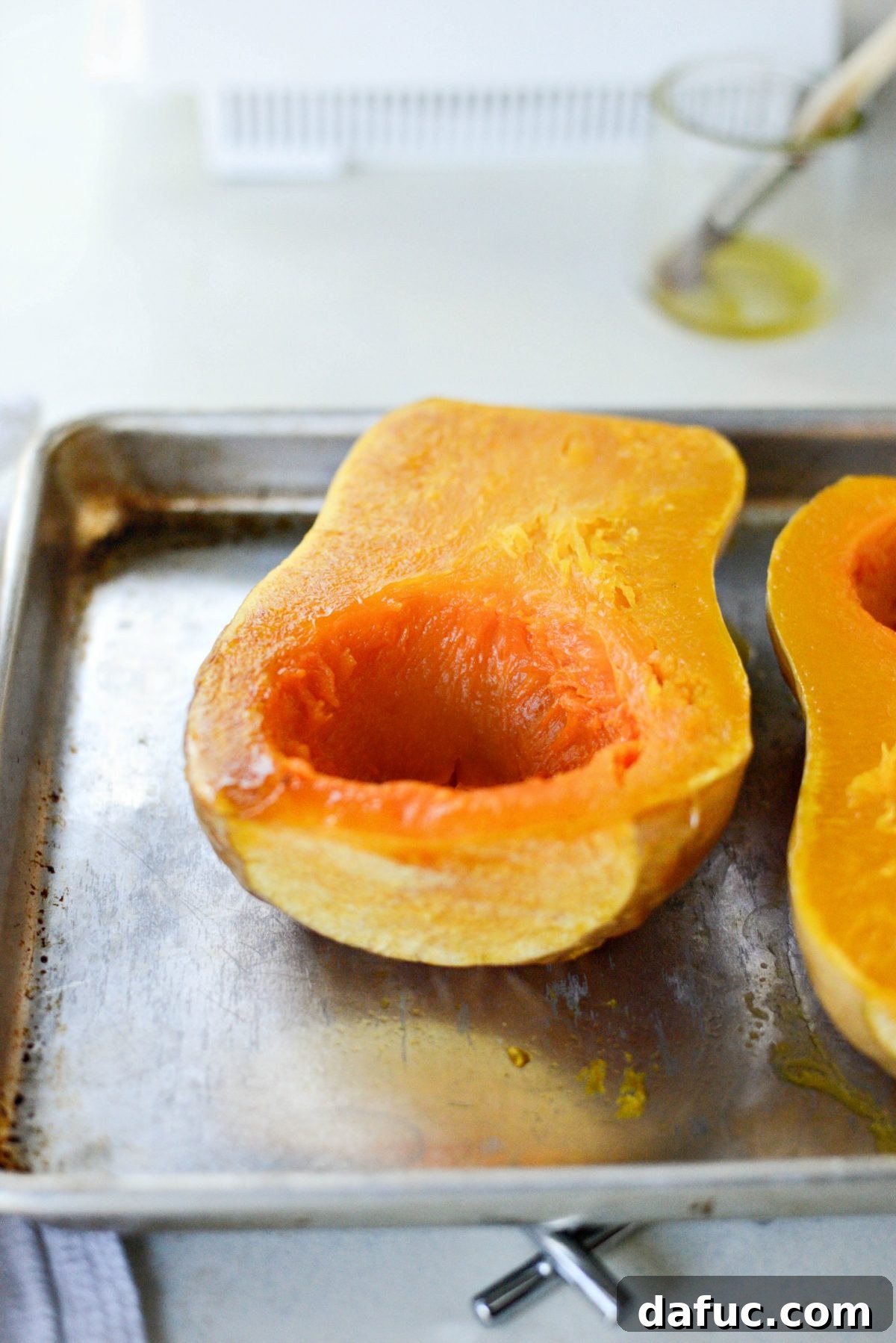 Two halves of perfectly roasted butternut squash, fork-tender and ready for scooping.