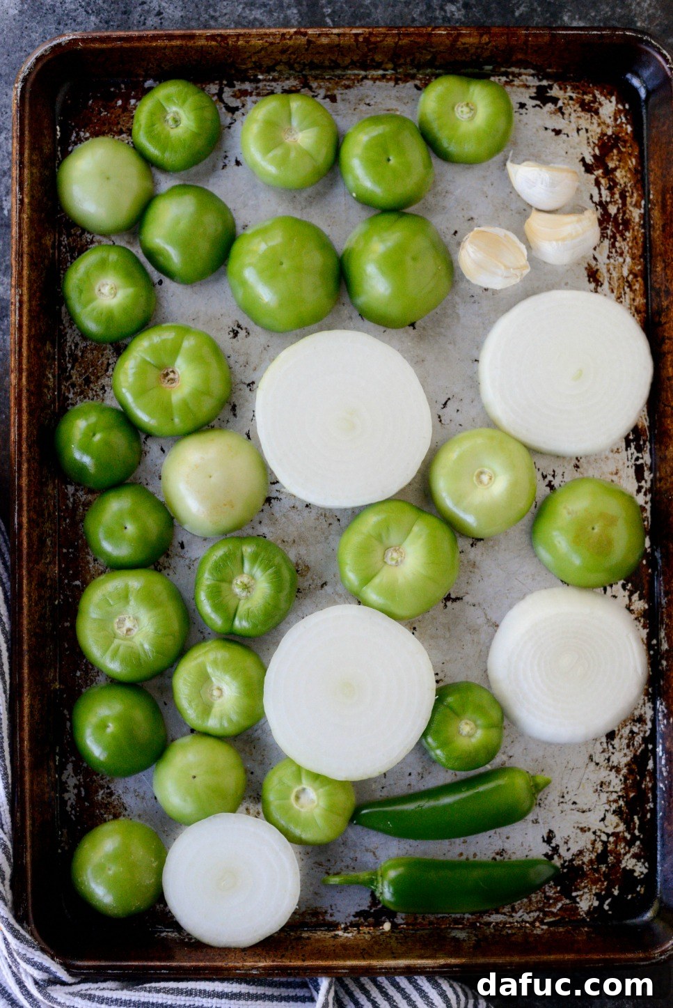 Effortless Zingy Tomatillo Salsa Verde 5 Tomatillos, jalapeño, onion, and garlic arranged on a baking sheet
