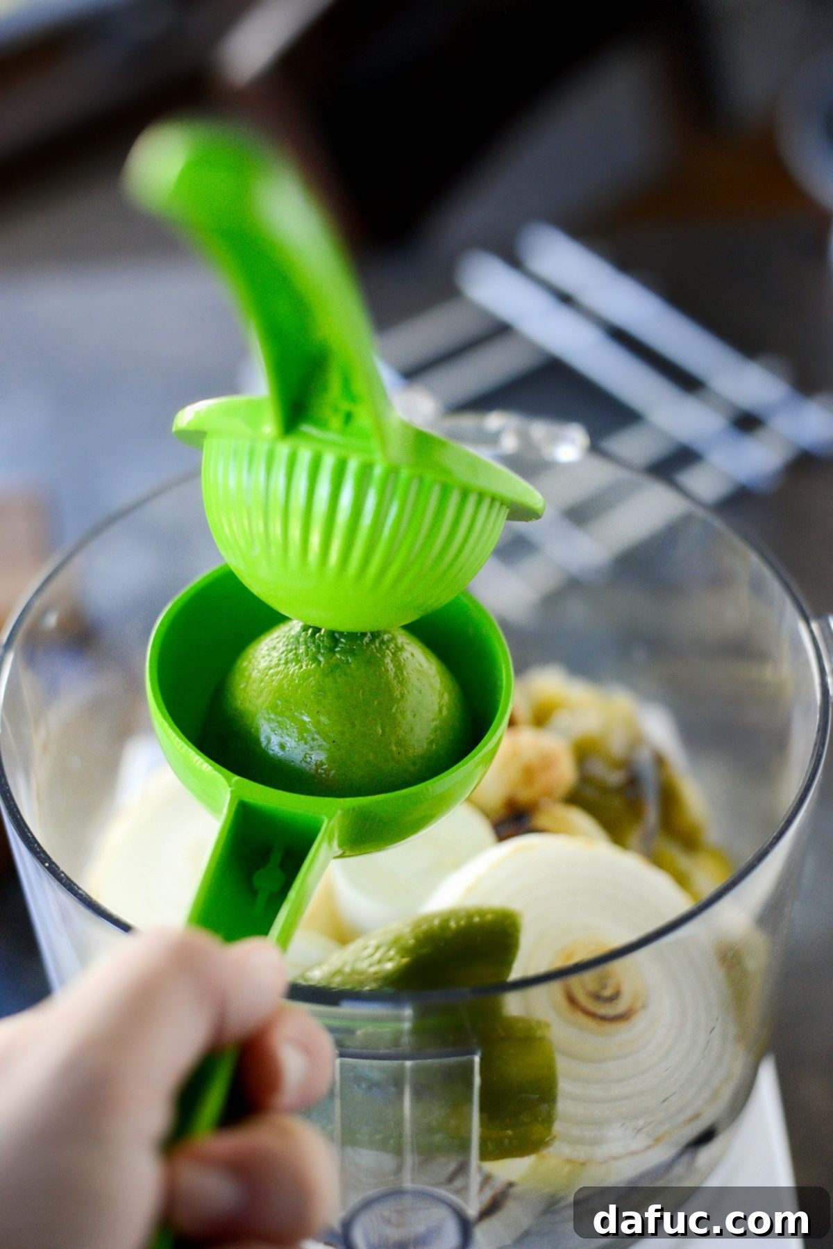 Effortless Zingy Tomatillo Salsa Verde 9 Fresh lime being squeezed into the food processor with roasted vegetables