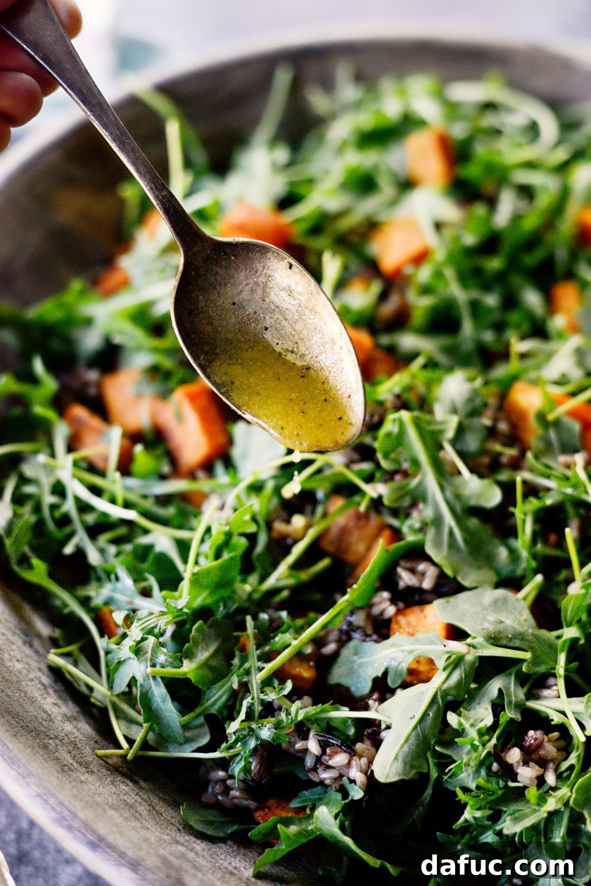 Drizzling dressing over Sweet Potato Wild Rice Arugula Salad