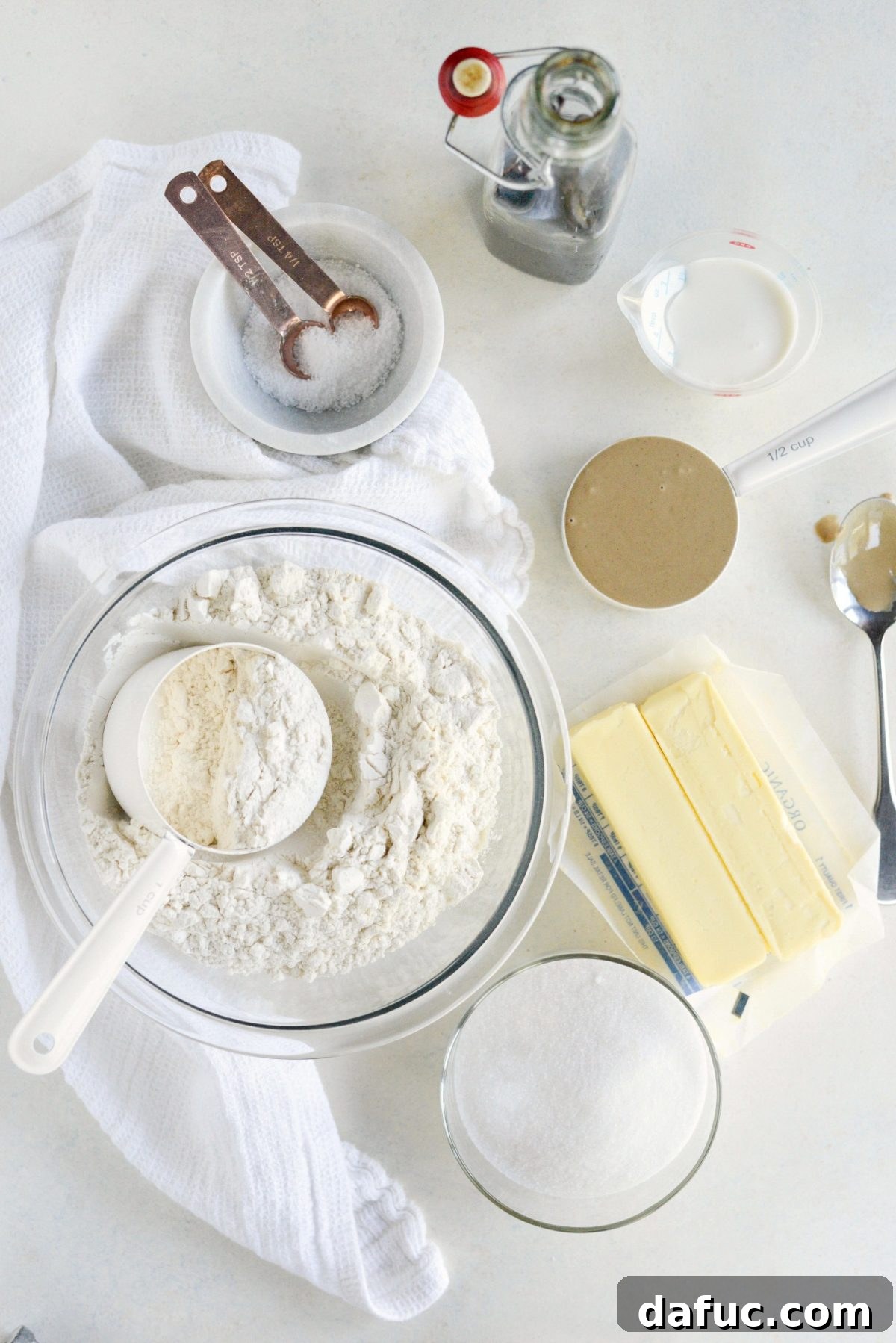 Ingredients for Tahini Shortbread Cookies - A meticulously arranged top-down view of all the necessary ingredients for making Tahini Shortbread Cookies, including softened butter, tahini, sugar, salt, vanilla extract, flour, and heavy cream, laid out on a clean surface.