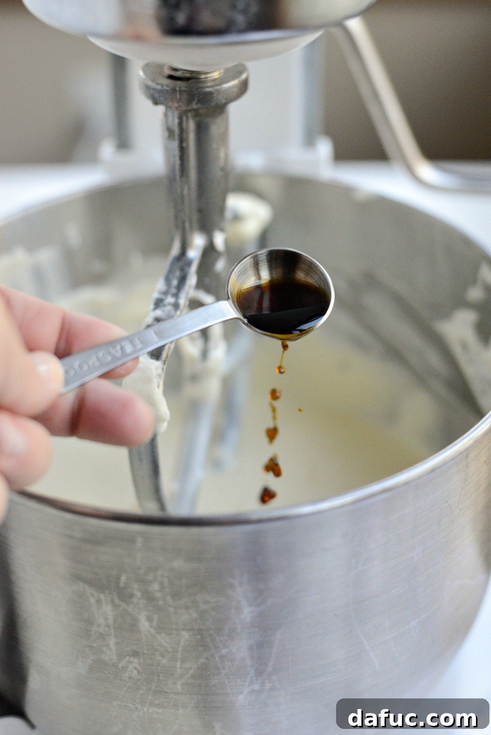 Tangy Goat Cheese Cheesecake with Tahini-Kissed Shortbread Base 13 Pure vanilla extract being poured into the cheesecake mixture, adding a rich aromatic note