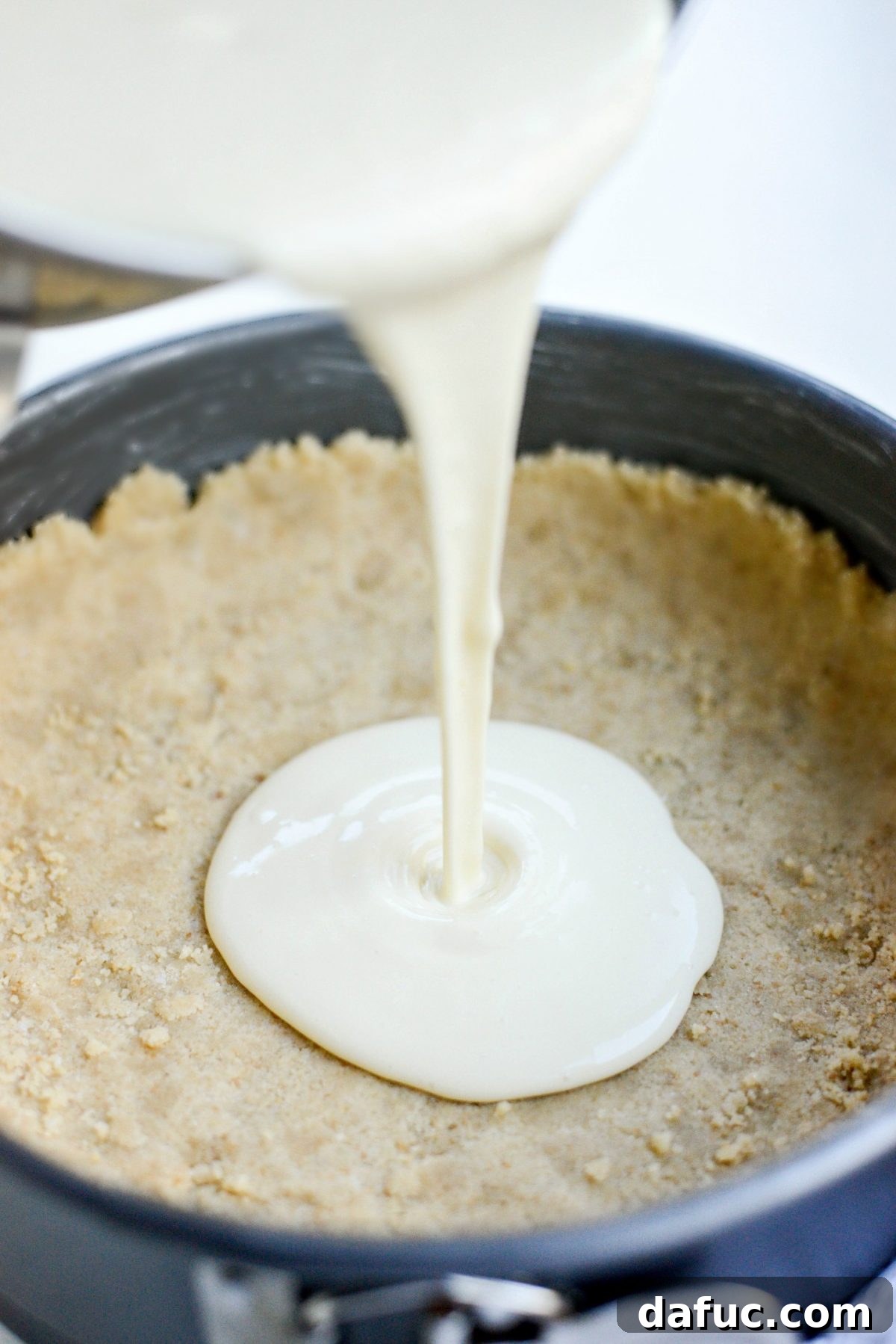 Tangy Goat Cheese Cheesecake with Tahini-Kissed Shortbread Base 14 Cheesecake filling being poured into the prepared tahini shortbread crust in a springform pan