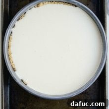 Tangy Goat Cheese Cheesecake with Tahini-Kissed Shortbread Base 15 Goat Cheese Cheesecake baking in the oven, with a slight golden hue on its surface