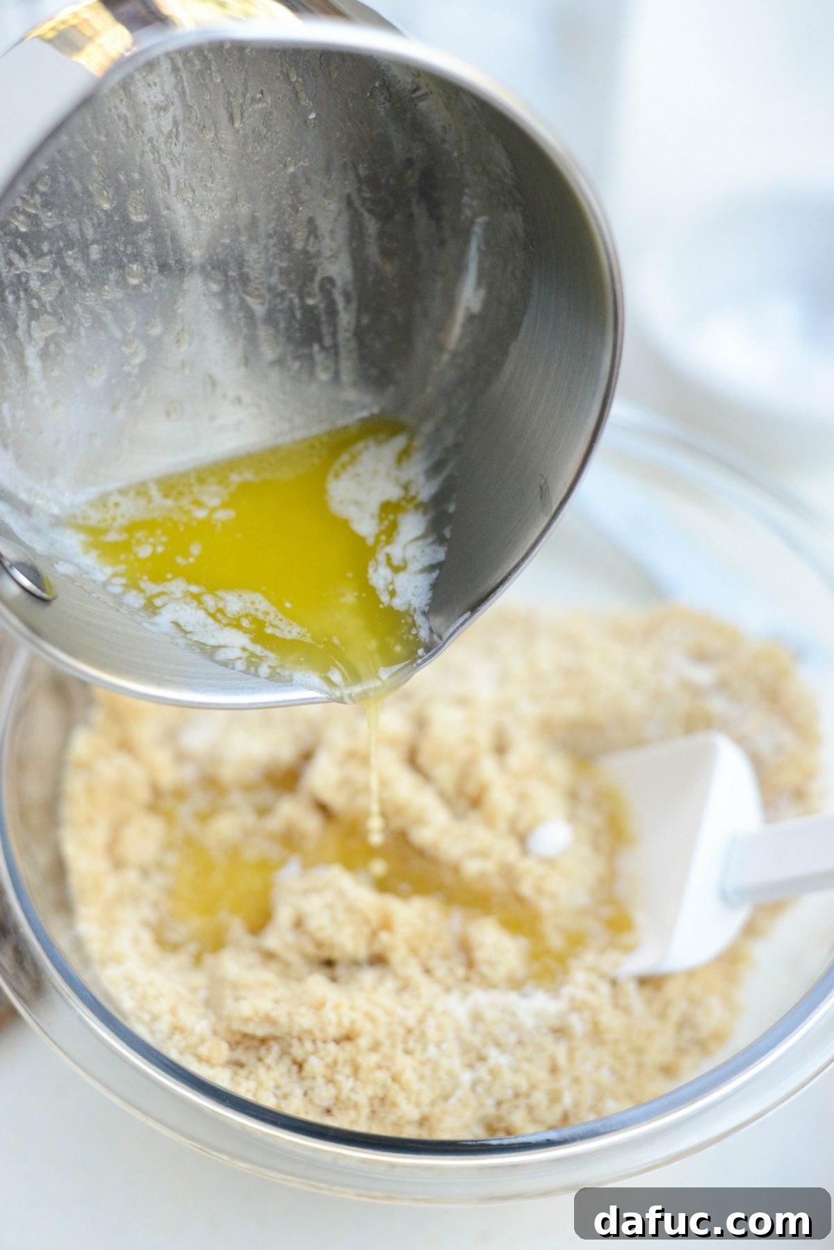 Tangy Goat Cheese Cheesecake with Tahini-Kissed Shortbread Base 5 Melted butter being poured into the crushed tahini shortbread cookie mixture for the cheesecake crust