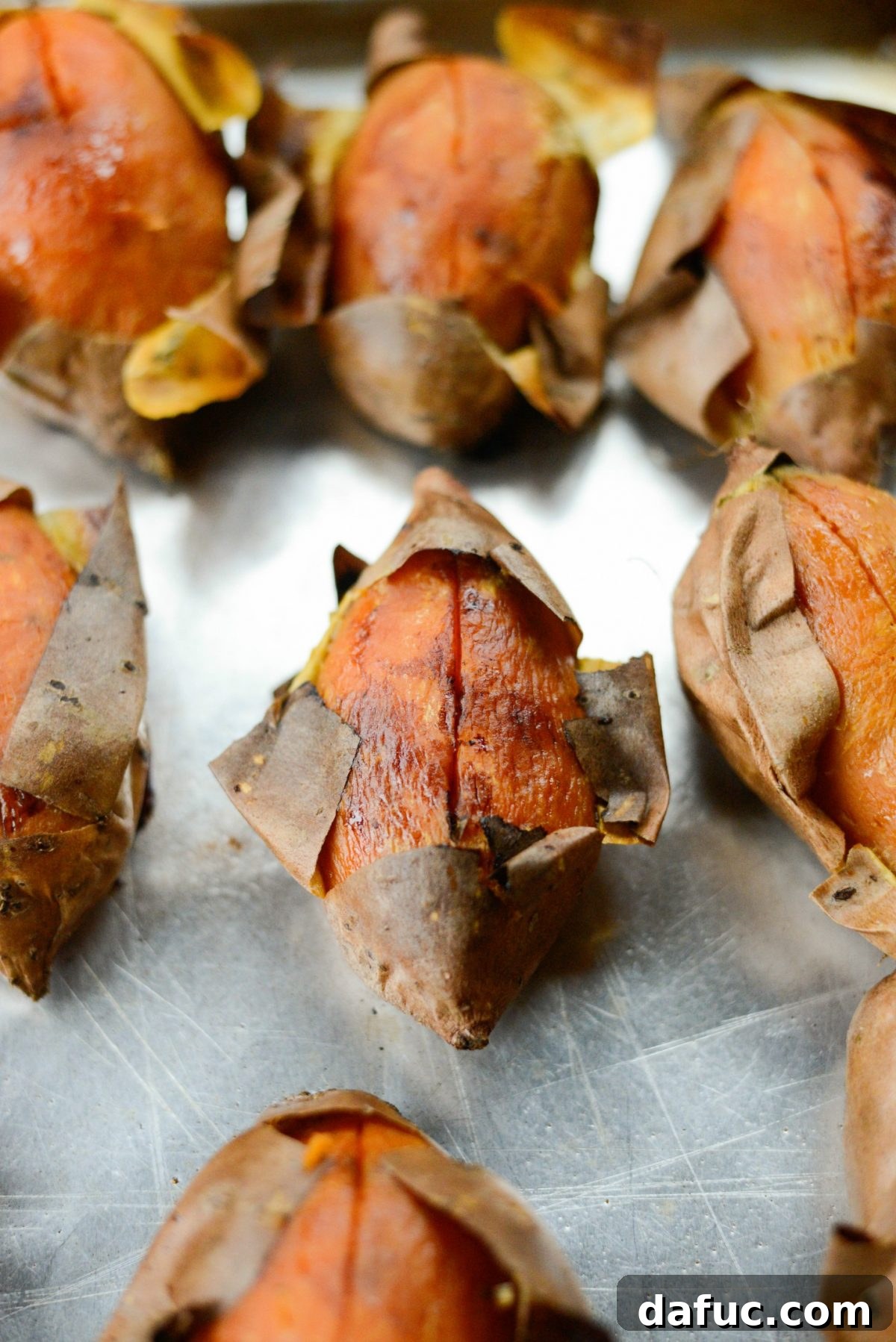 Silky Maple Sweet Potato Mash 5 Whole roasted sweet potato on a baking sheet, showing a slightly caramelized skin