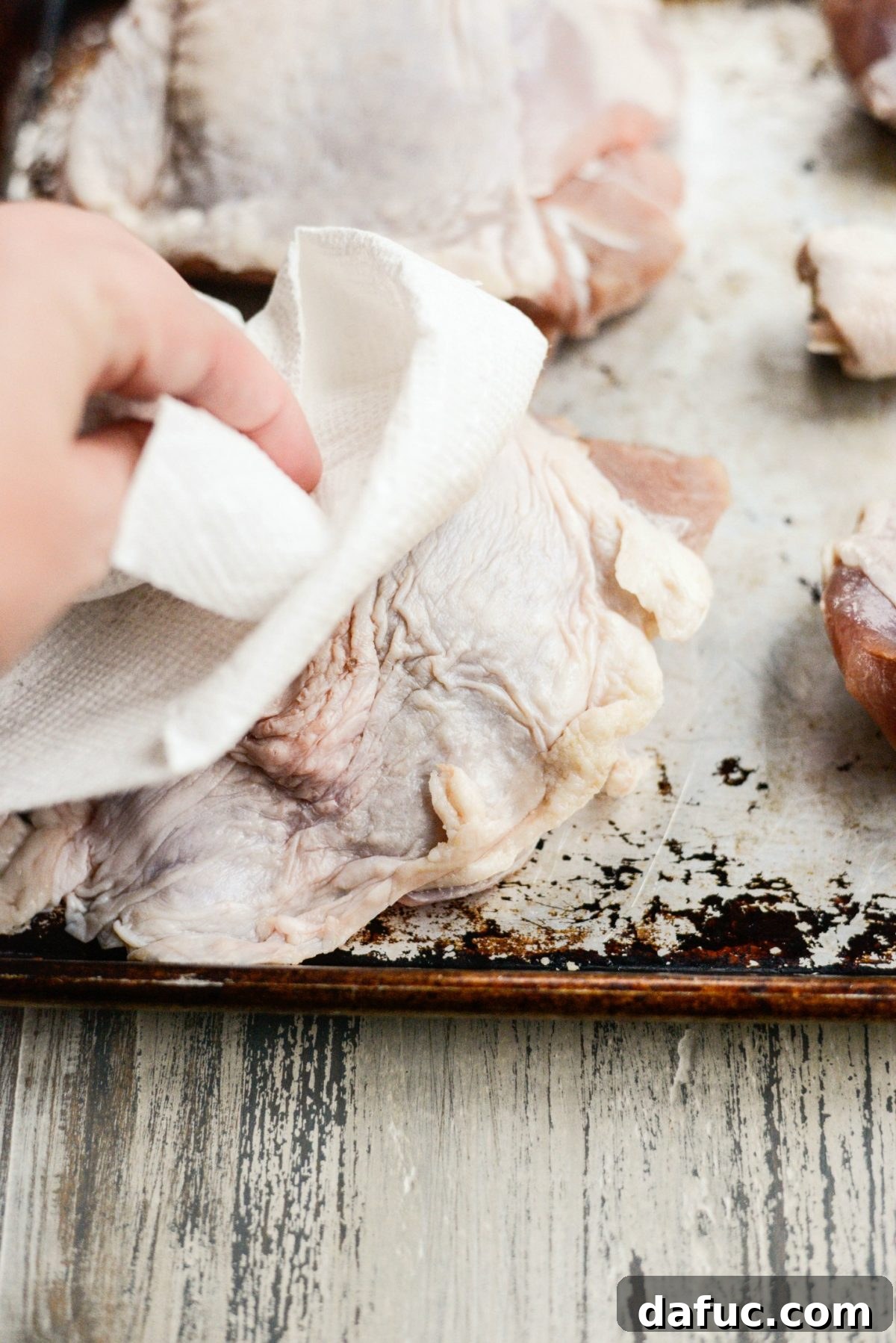 Patting turkey pieces dry with paper towels to prepare for roasting