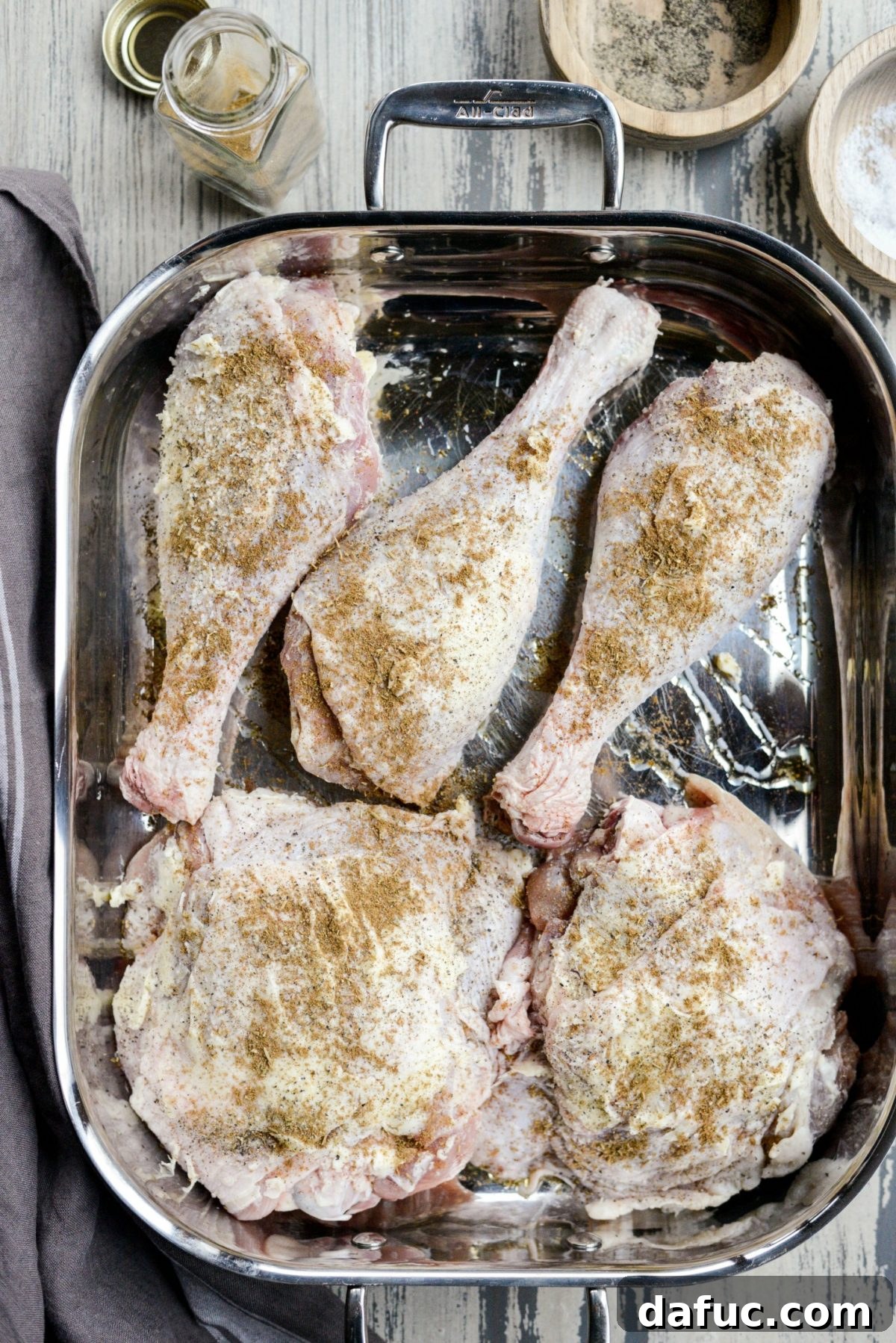 Roasting pan filled with perfectly seasoned turkey thighs and drumsticks, ready for the oven