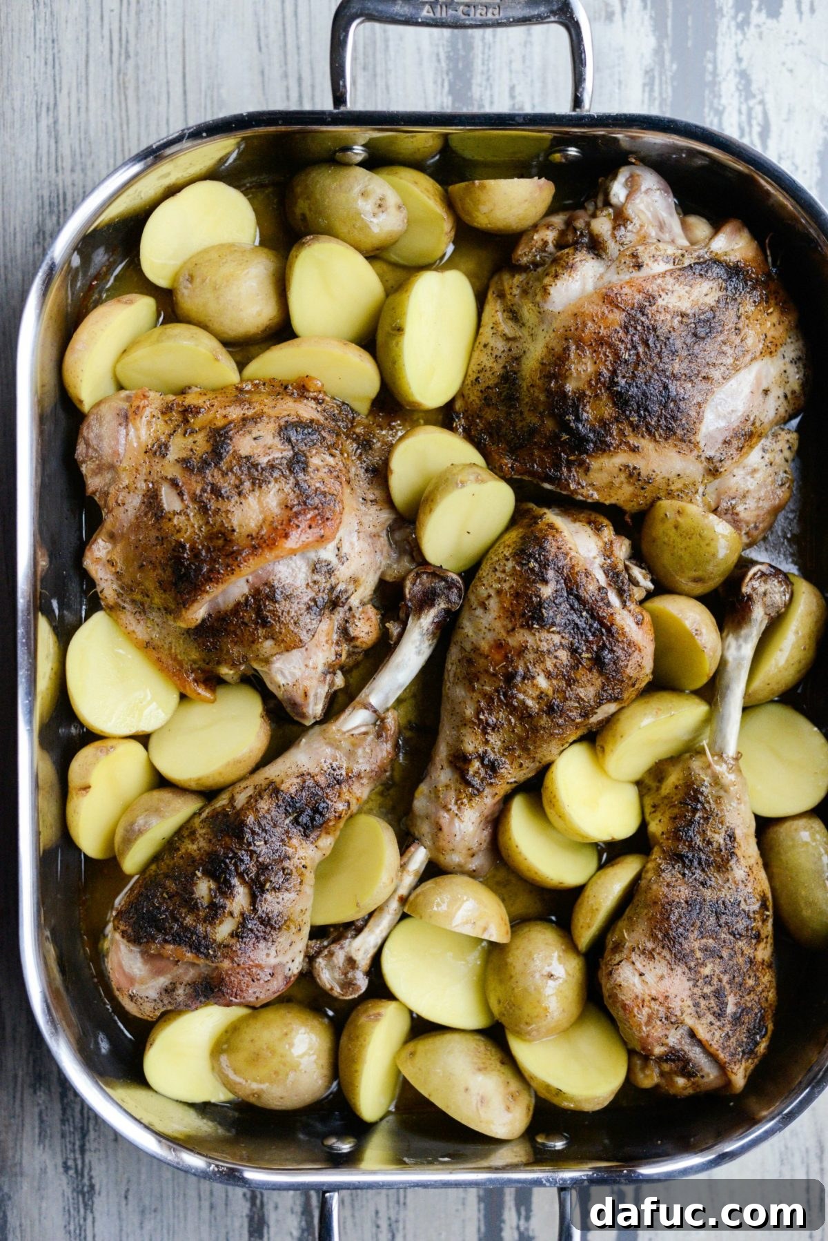 Adding halved baby Yukon gold potatoes around the partially roasted turkey in the pan