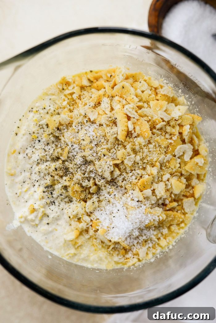 Add corn, creamed corn, cracker crumbs, salt and pepper to egg mixture - Combining All Ingredients