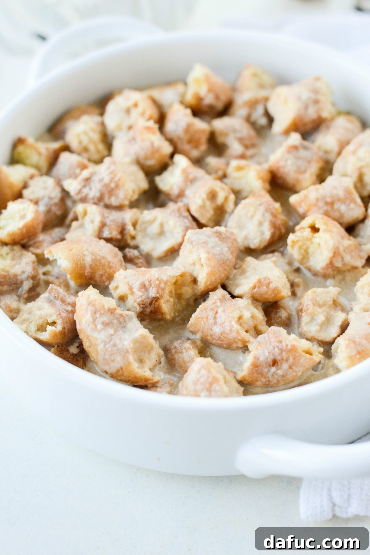 Autumn Spiced Doughnut Bread Pudding 14 Using hands to press down doughnut pieces to fully absorb the custard mixture