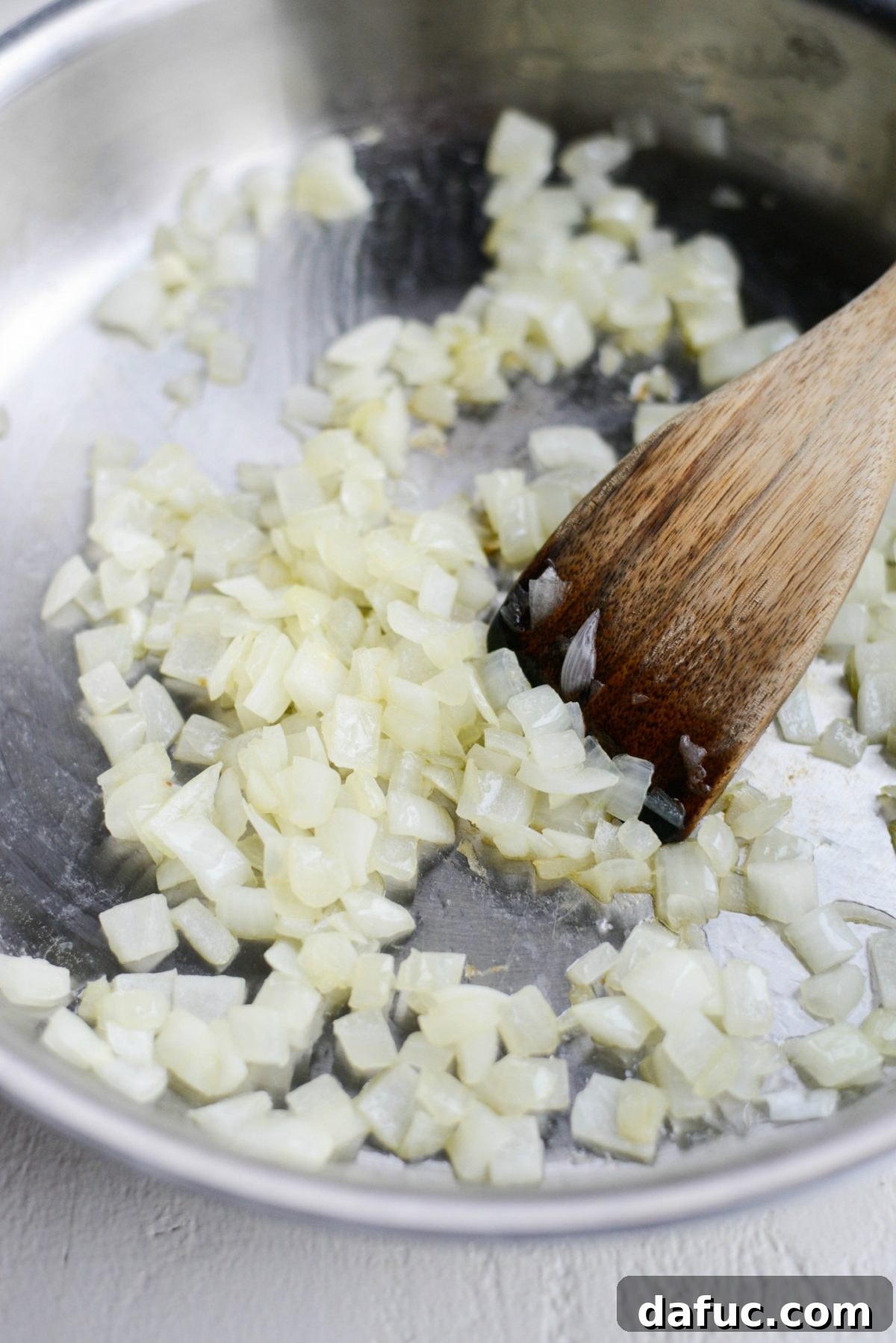Diced onions caramelizing in olive oil, ready for garlic