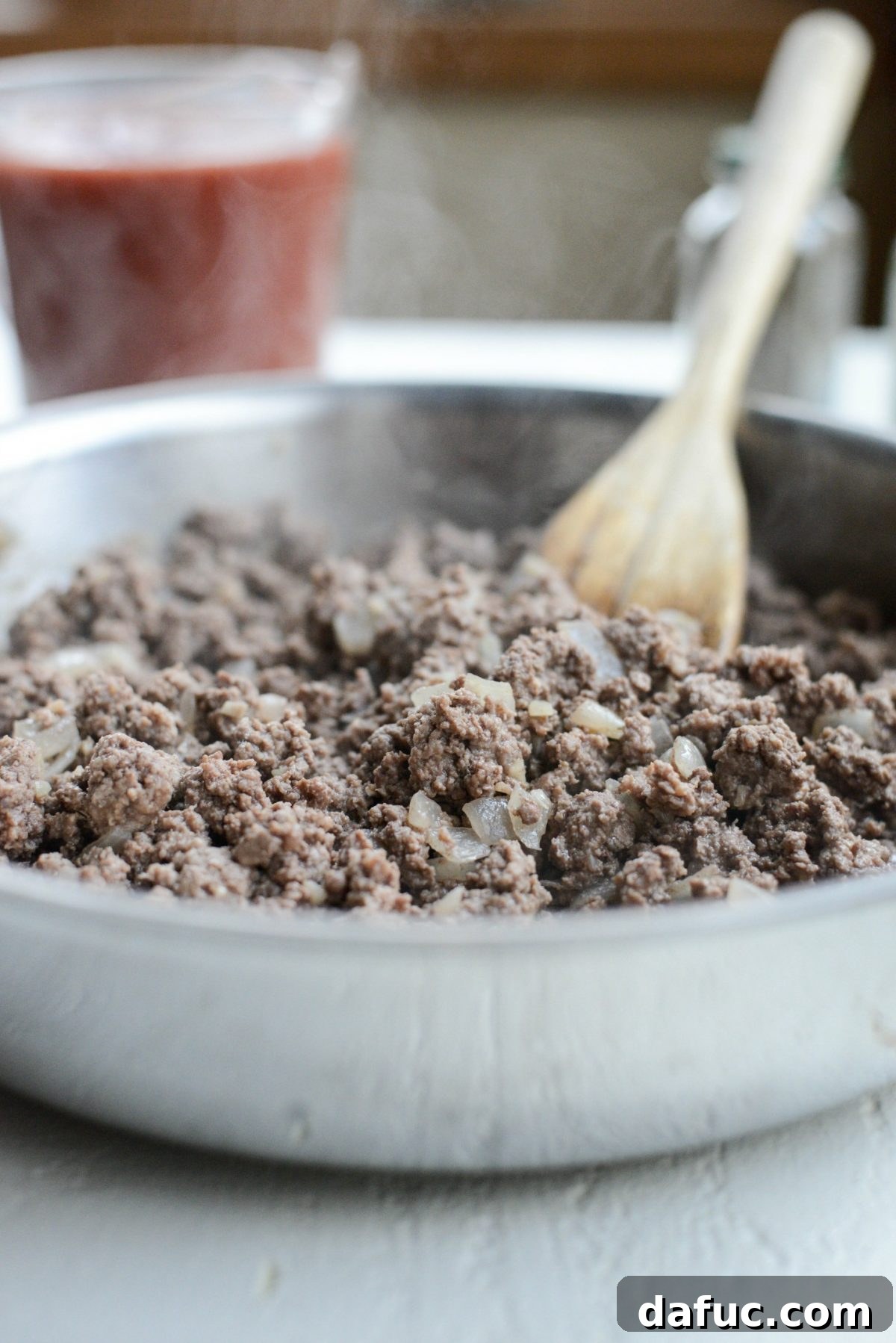 Ground beef browning in a skillet with onions and garlic