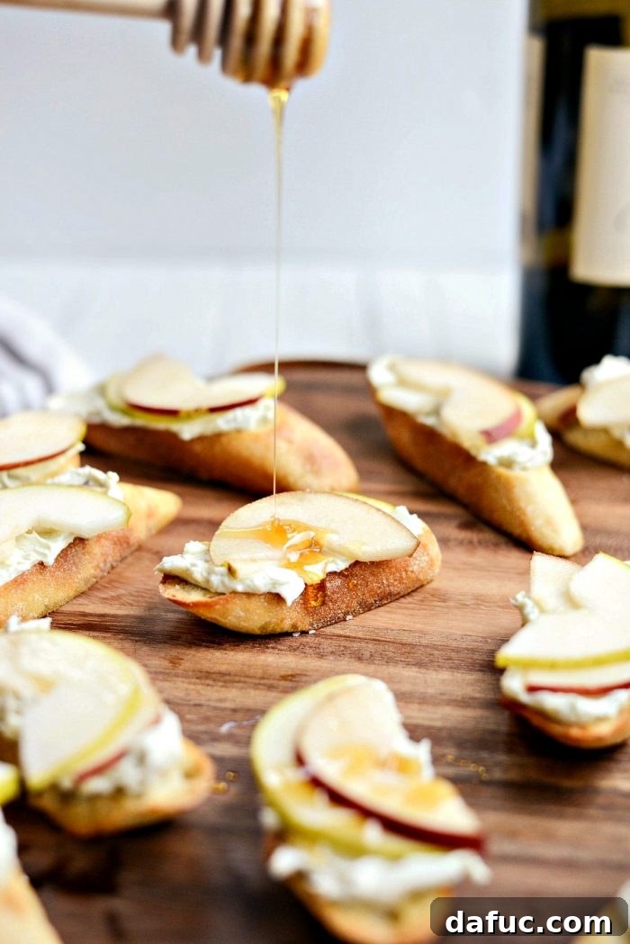 Drizzling golden honey over assembled blue cheese and pear crostini.