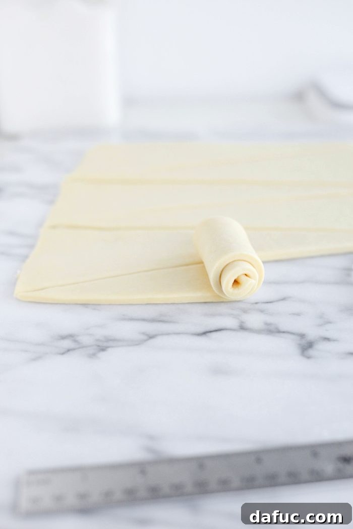 Effortless Homemade Croissant Perfection 22 Rolling the croissant dough from the wide end towards the point