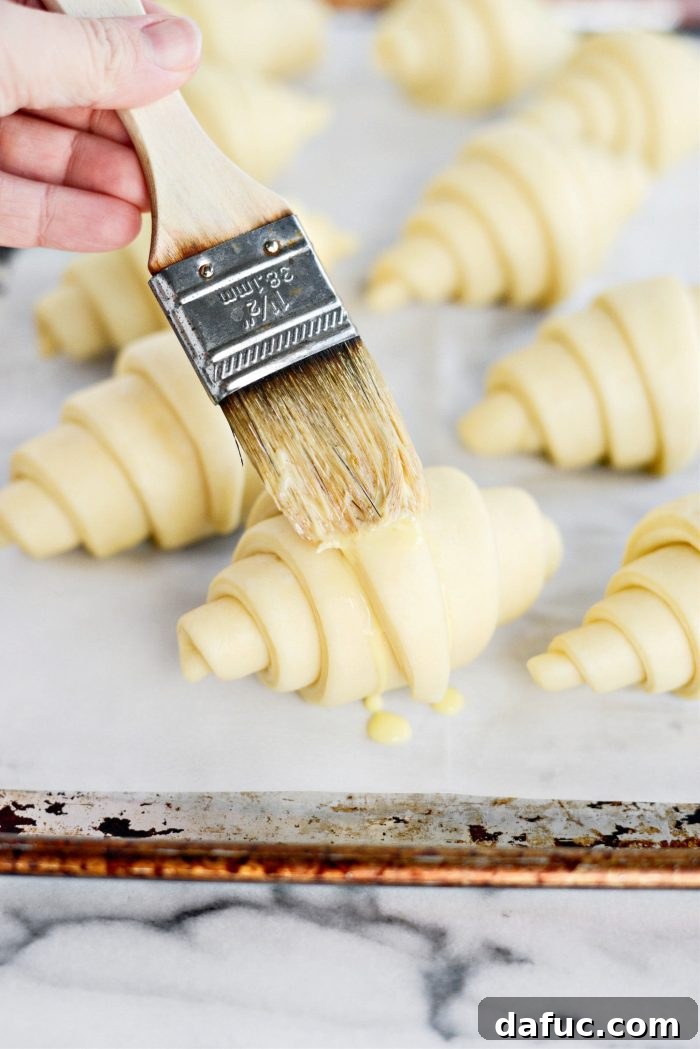 Effortless Homemade Croissant Perfection 27 Brushing risen croissants with an egg wash