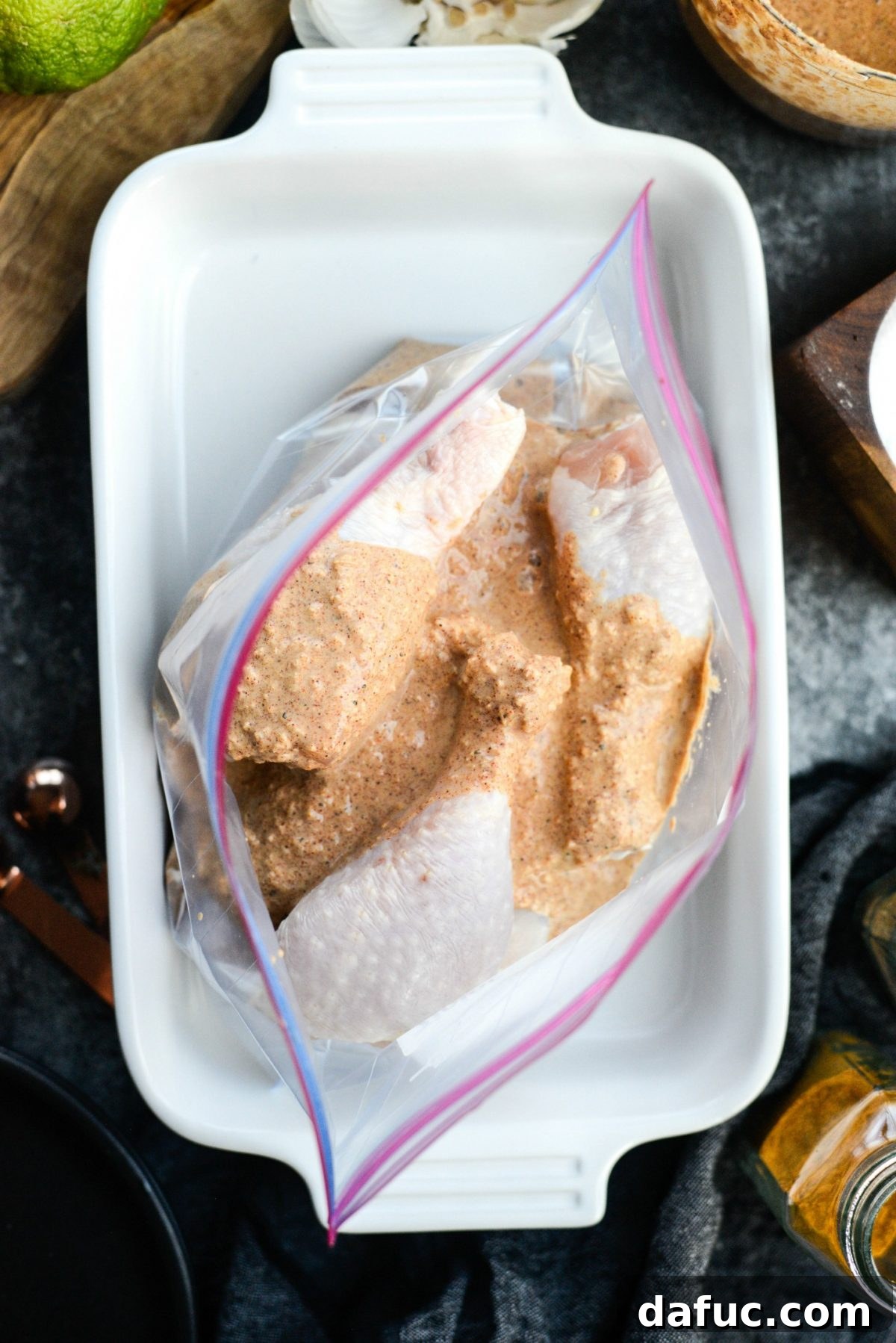 Pouring half of the tandoori marinade over chicken drumsticks in a resealable bag.