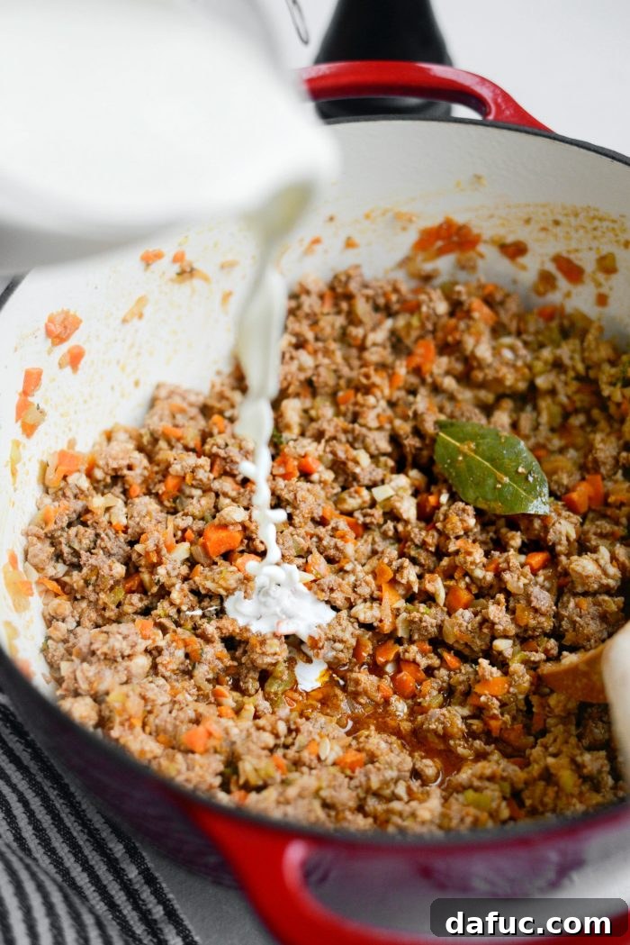 Pouring heavy cream into the bolognese sauce