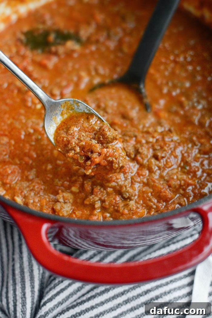 Tasting and seasoning the bolognese sauce with salt and pepper