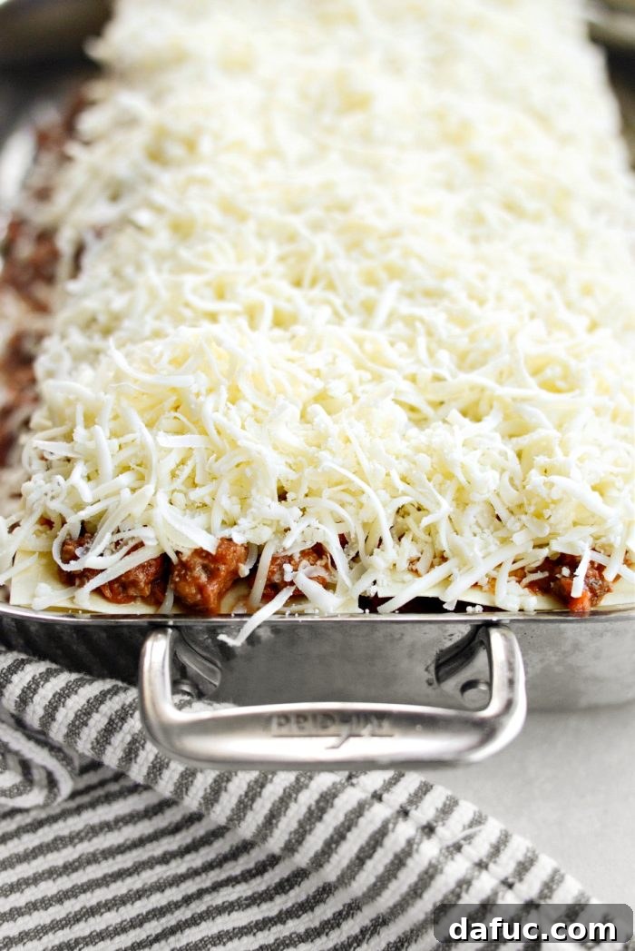Topping the lasagna with remaining mozzarella cheese before baking