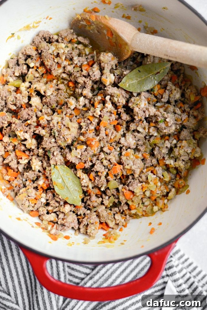Breaking up ground meat with a wooden spoon until no longer pink