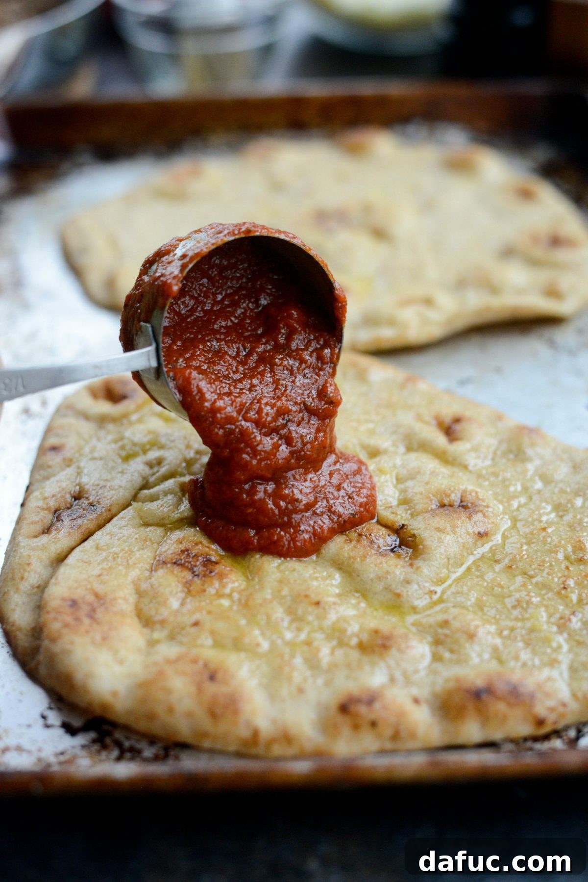 Levantine Lamb Margherita Pizza 9 Marinara sauce being poured and divided onto the individual naan breads.
