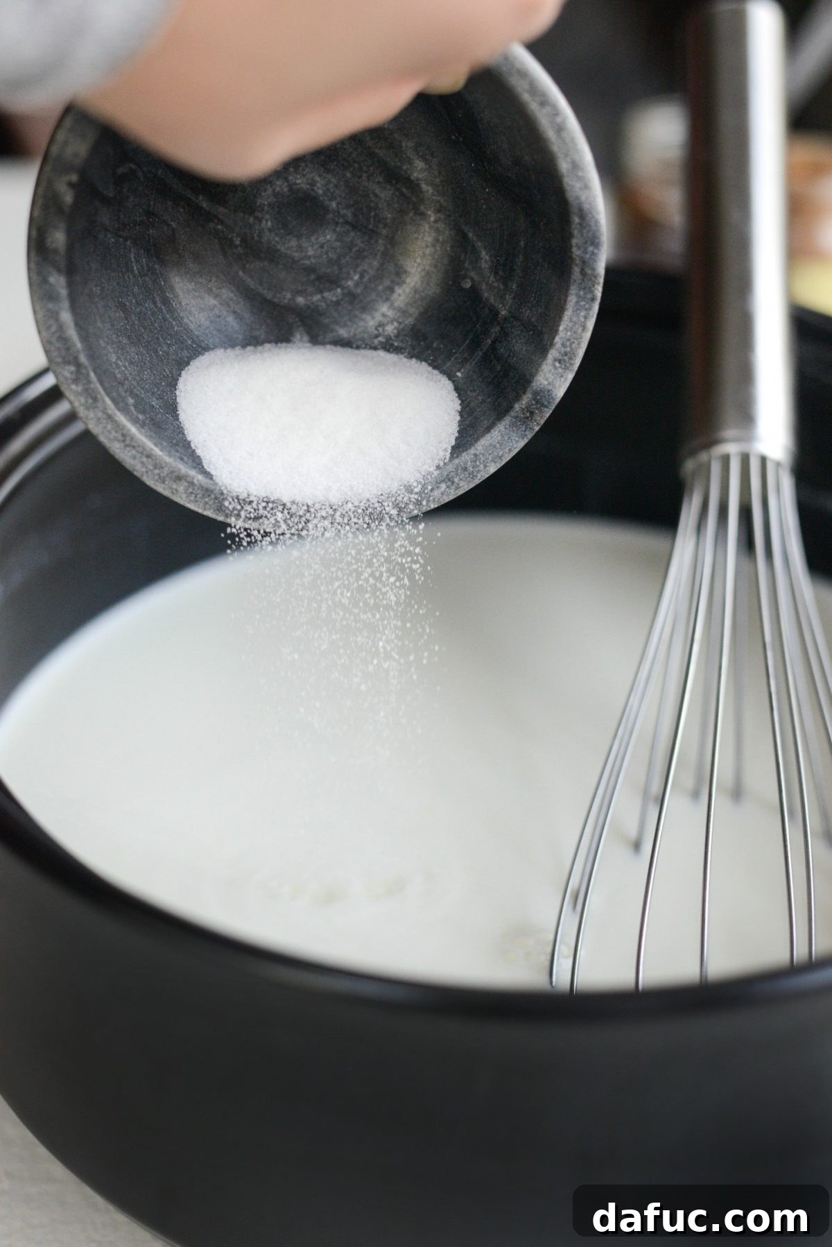 Mocha Magic 10 Granulated sugar being whisked into the hot milk and cream mixture in a pot