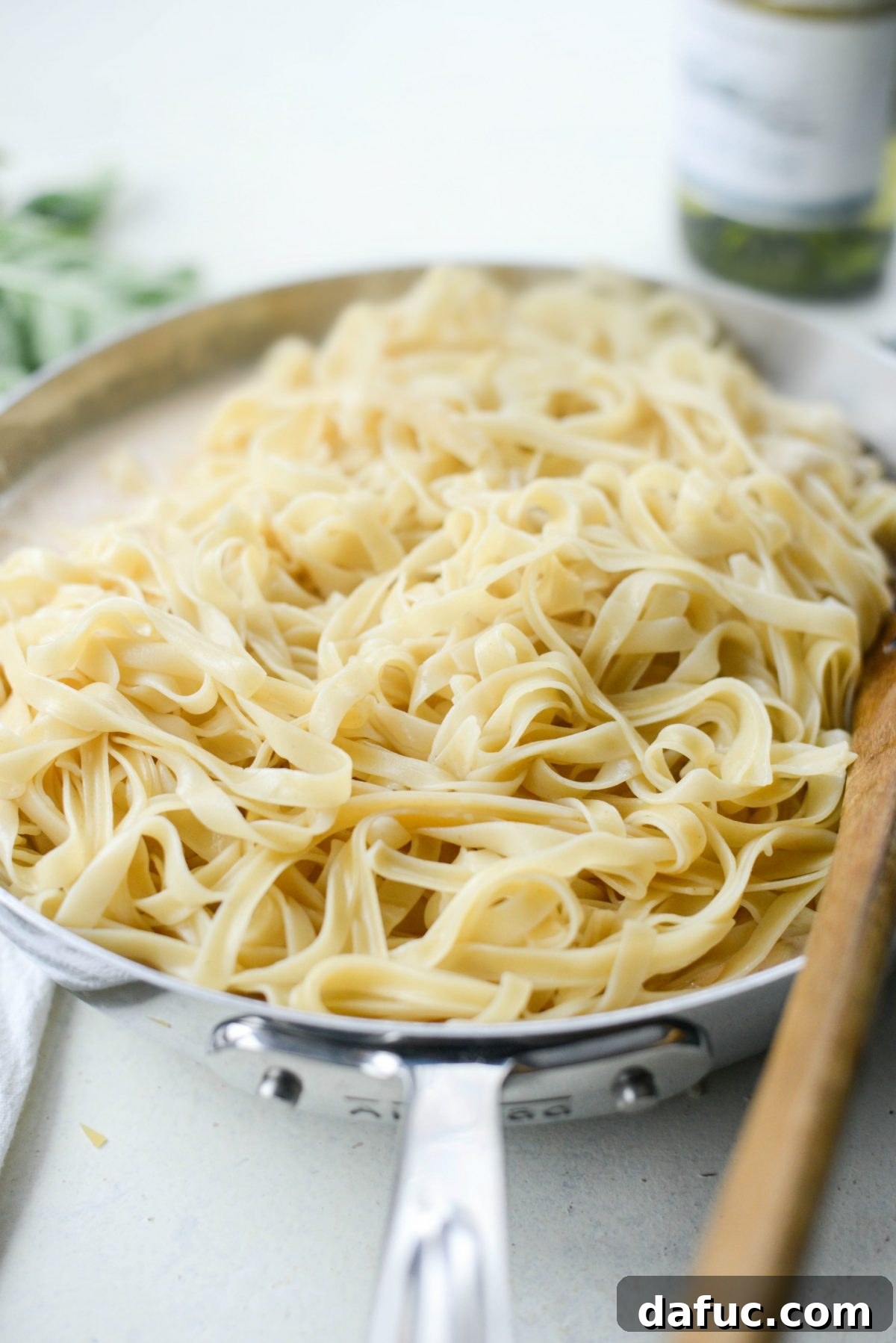 Cooked fettuccine noodles being added to the creamy Christmas sauce.