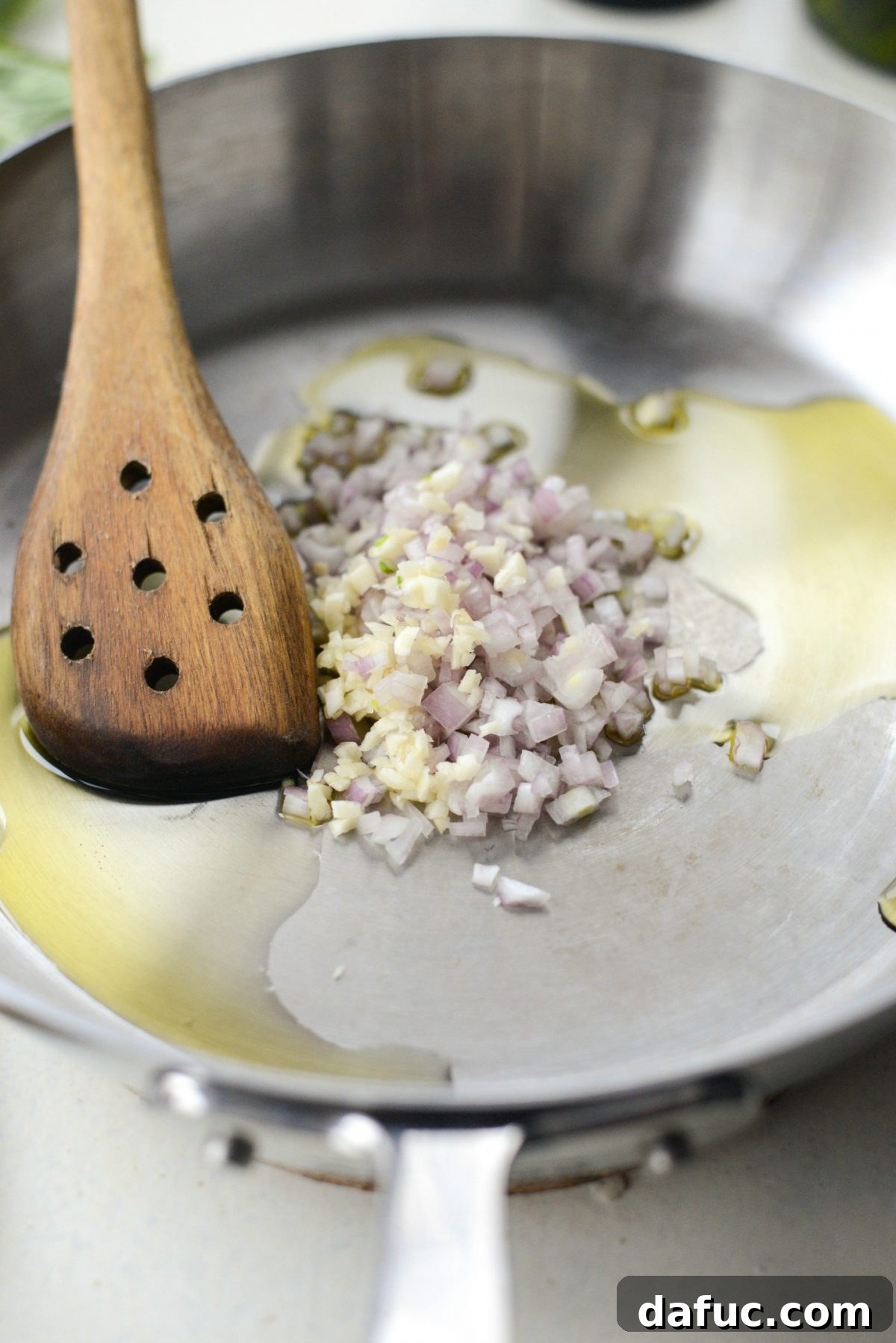 Finely minced shallots and garlic sizzling in olive oil in a pan.