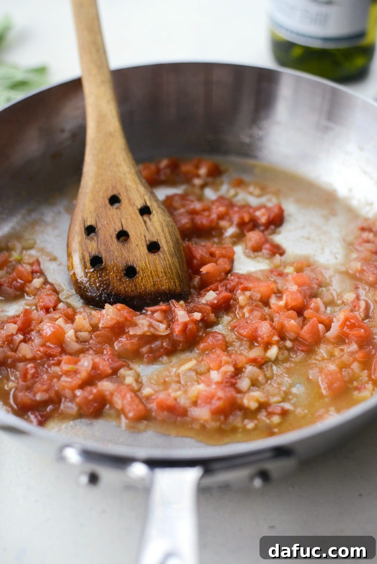 Stirring the white wine and tomato mixture as it reduces in the pan.
