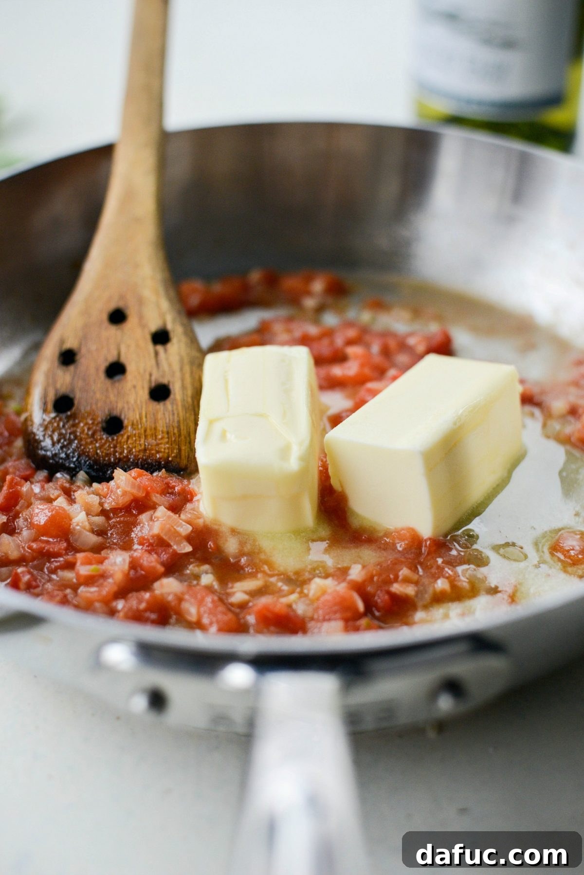 Unsalted butter melting into the simmering sauce mixture.