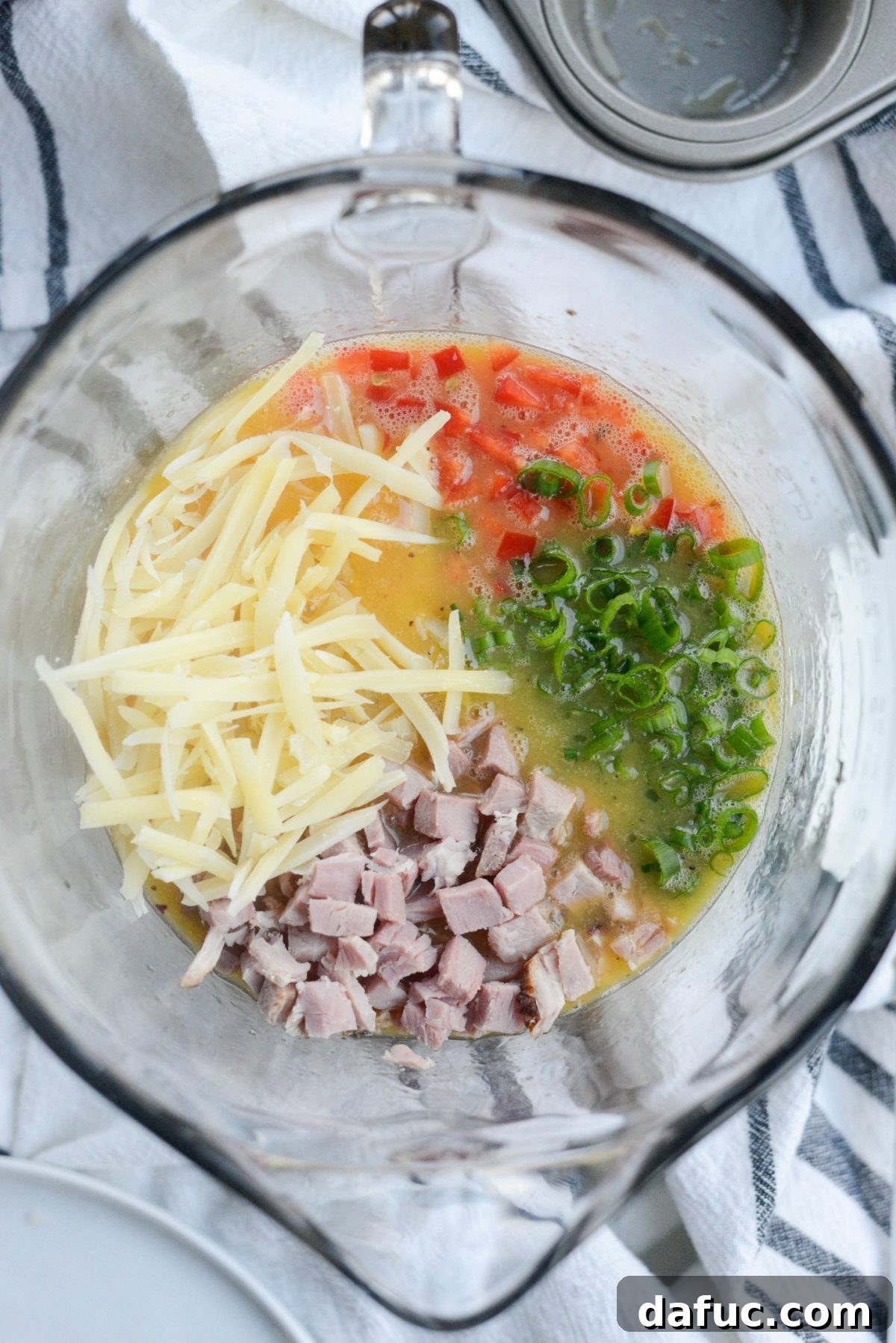 Adding ham, cheese, red bell pepper, and green onion to the egg mixture