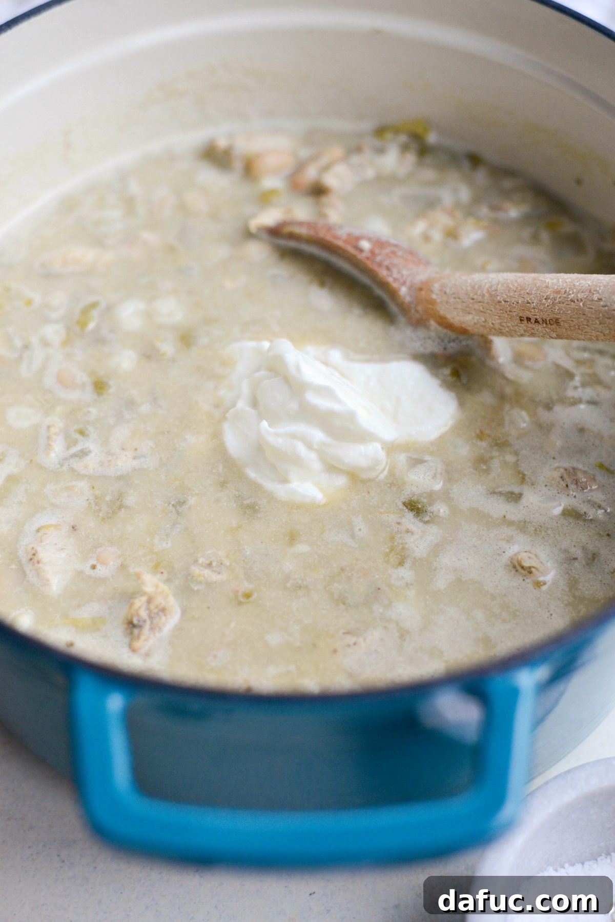 Stirring plain nonfat Greek yogurt into the simmering white chicken chili.