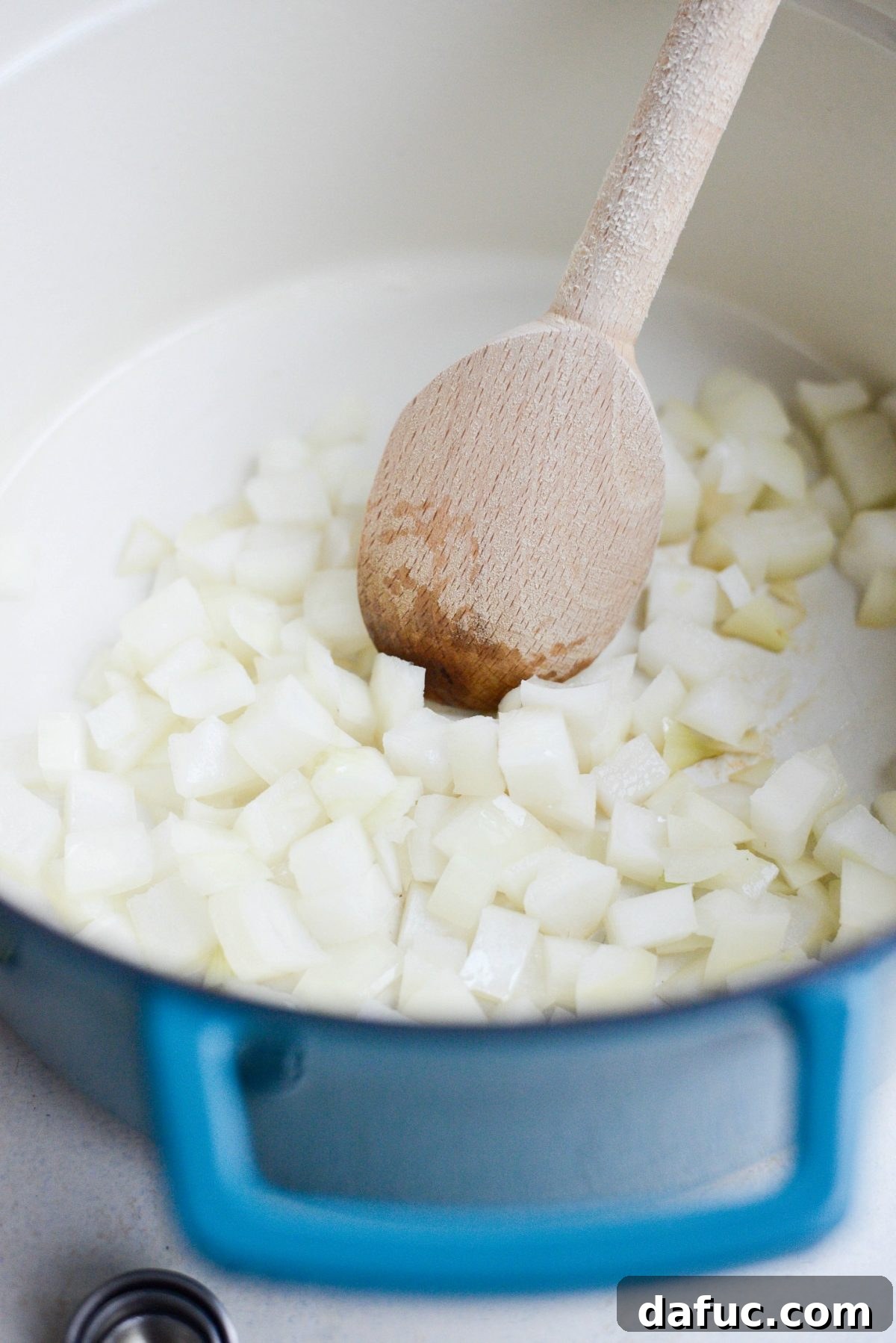 Sautéing diced yellow onions in olive oil in a large Dutch oven.