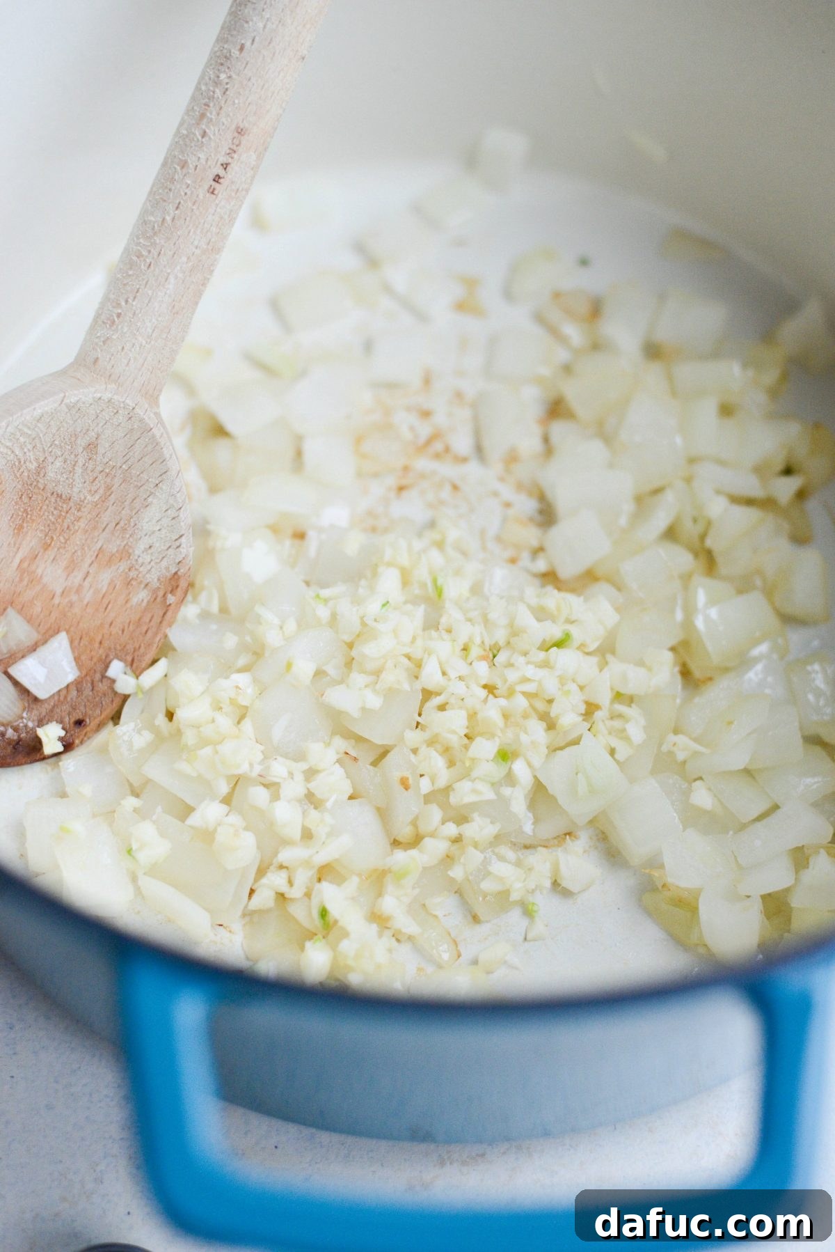 Adding minced garlic to softened onions in the pot.