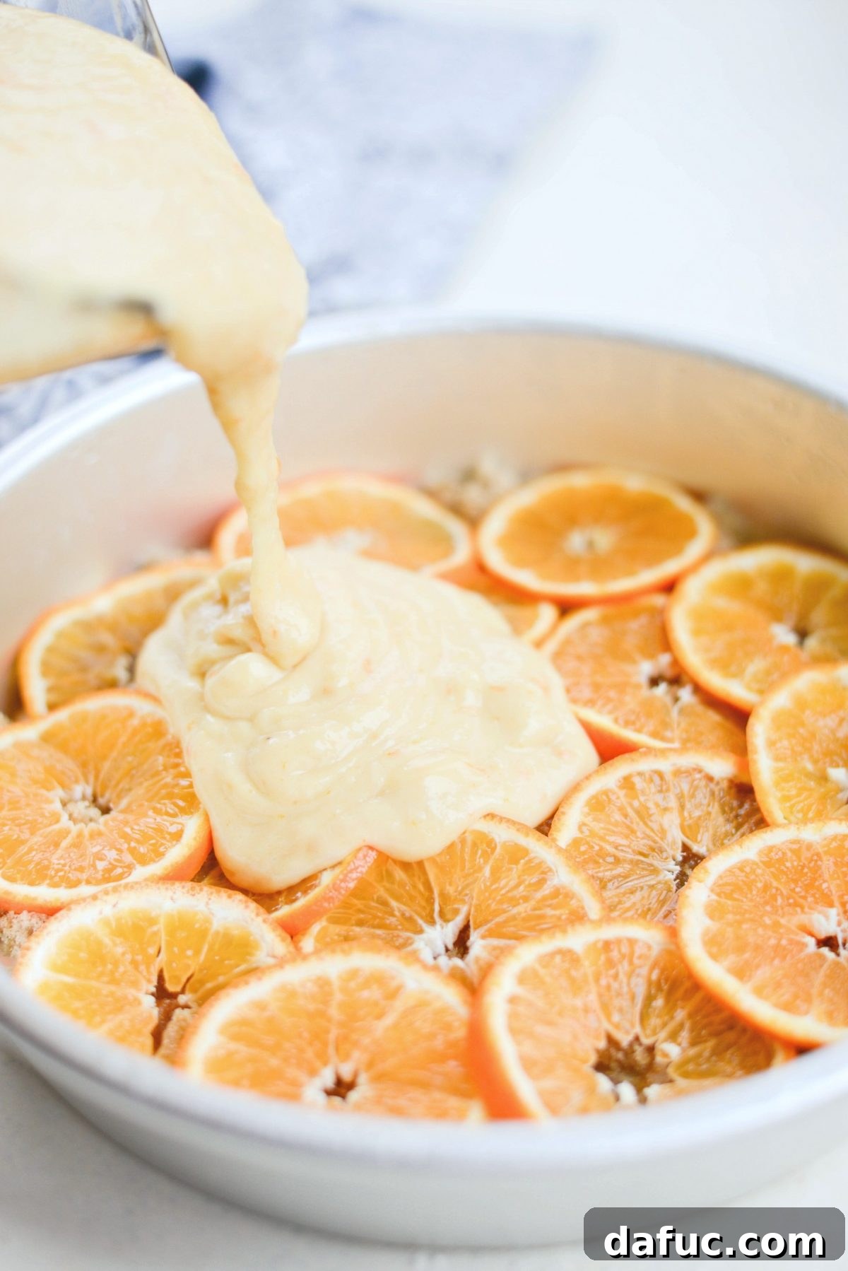 Golden Clementine Bliss Cake 14 Pouring clementine cake batter over thinly sliced clementines in a cake pan