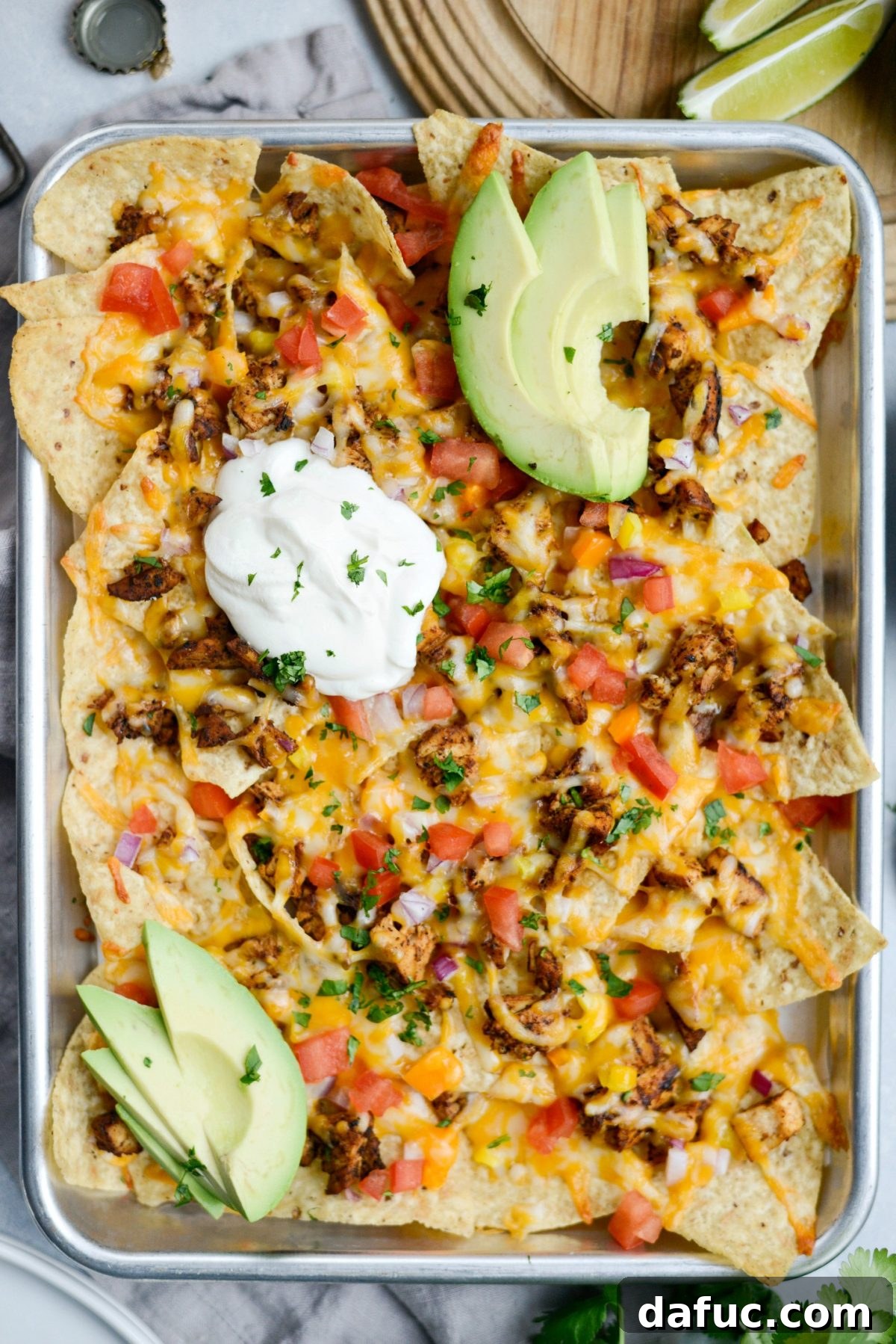 Baked Mexicali Chicken Sheet Pan Nachos, glistening with melted cheese and ready for fresh toppings.