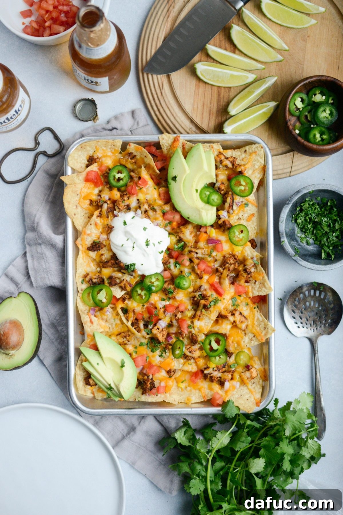 A serving of Mexicali Chicken Sheet Pan Nachos on a plate with an appetizing spread of toppings.