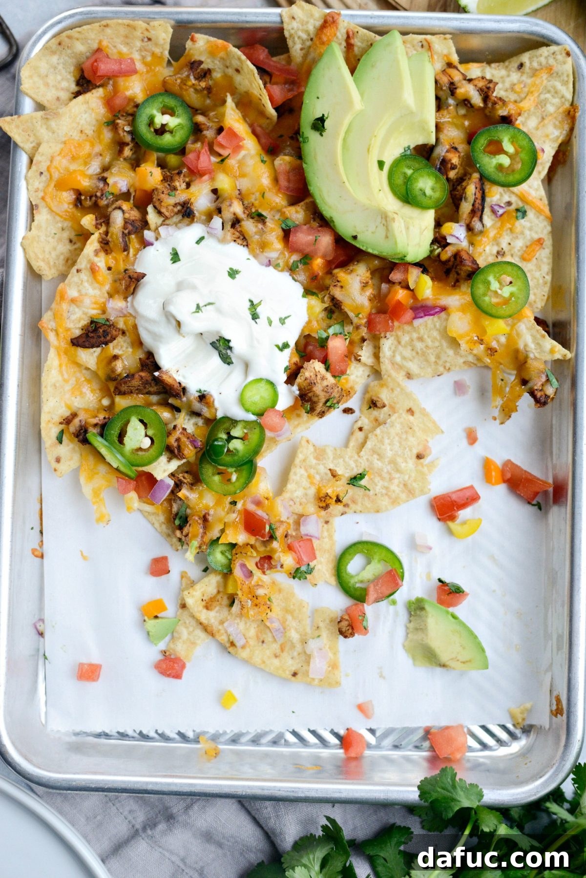 Final plated serving of Mexicali Chicken Sheet Pan Nachos, showcasing all the delicious layers and fresh garnishes.