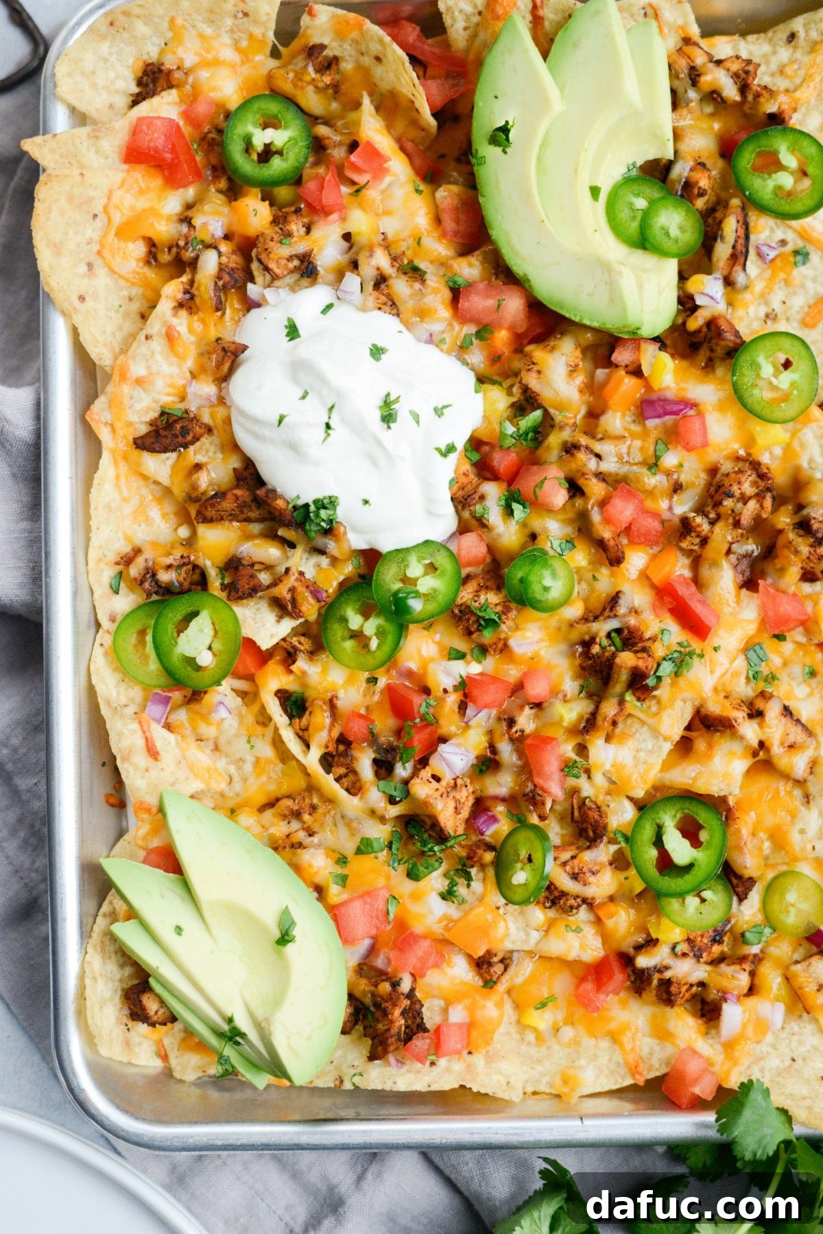 A close-up of the delicious Mexicali Chicken Sheet Pan Nachos showing the texture and variety of ingredients.