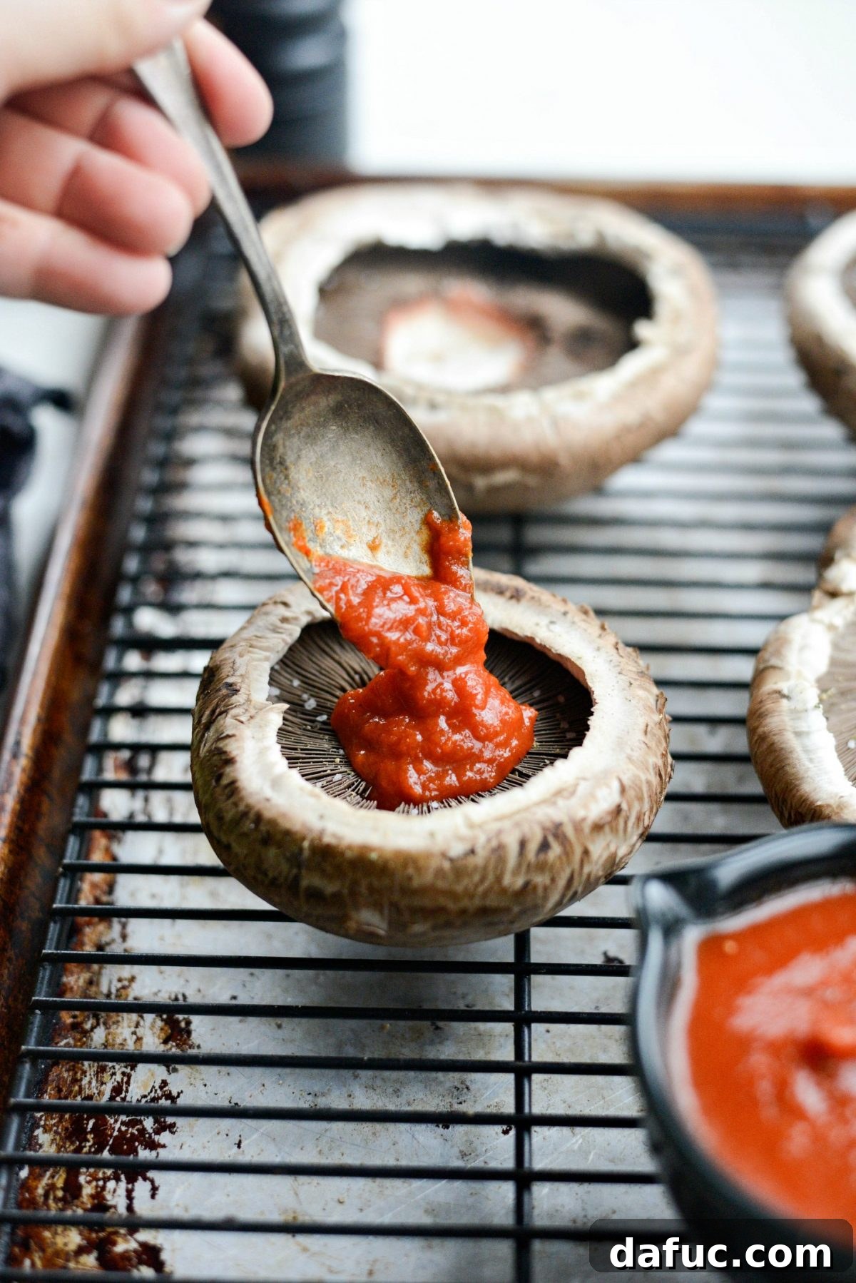 Caprese Stuffed Roasted Portobello Caps 7 Adding marinara sauce to portobello mushroom caps
