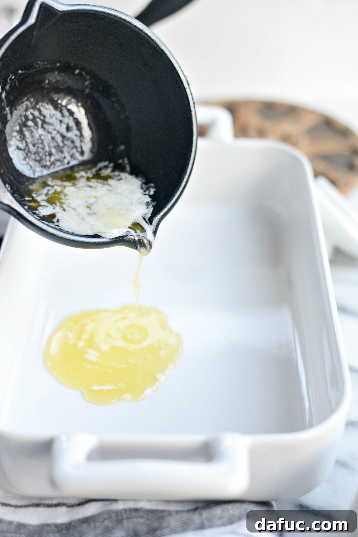 Melted butter being swirled in an oven-safe baking dish