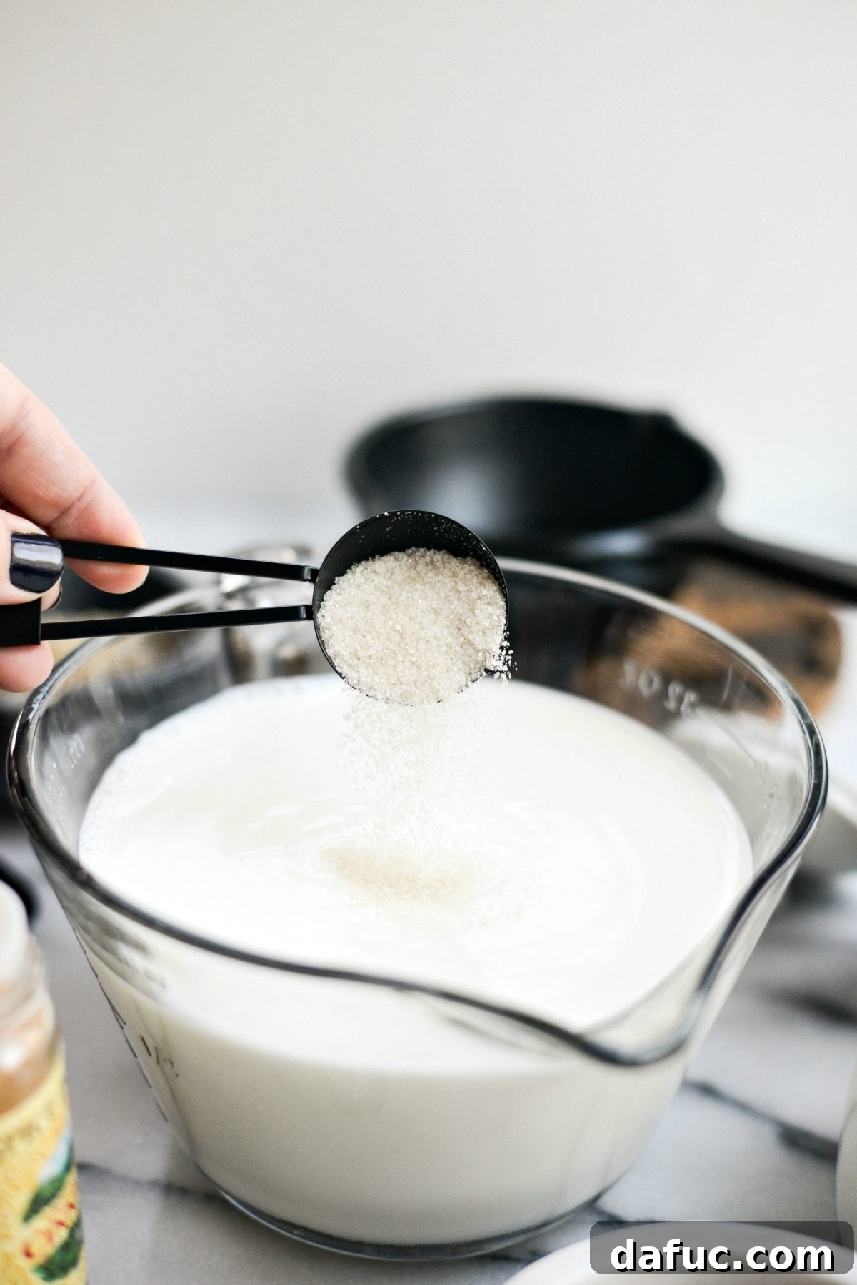 Adding sugar to milk in a bowl for rice pudding