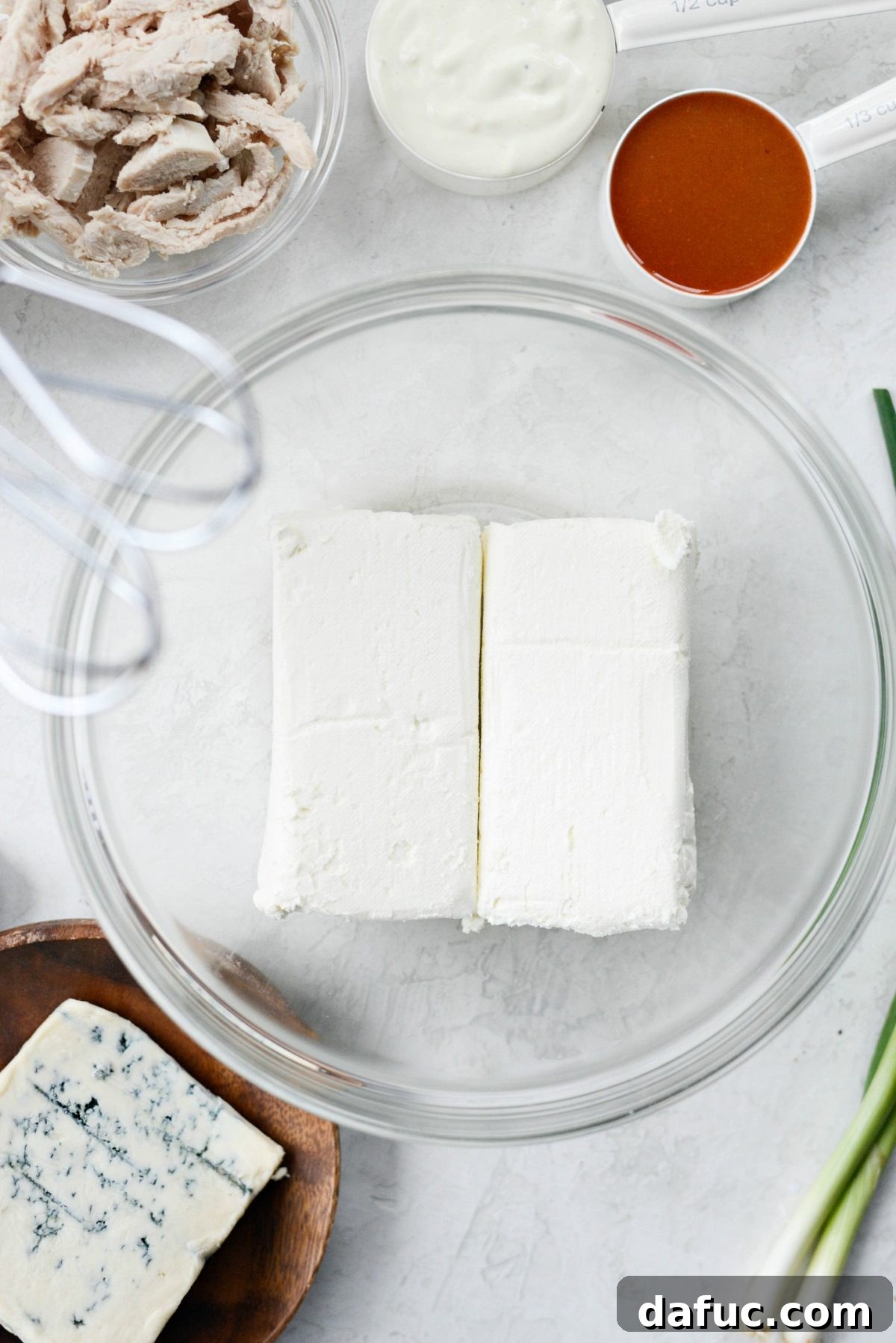 Cream cheese in mixing bowl, ready for buffalo chicken dip
