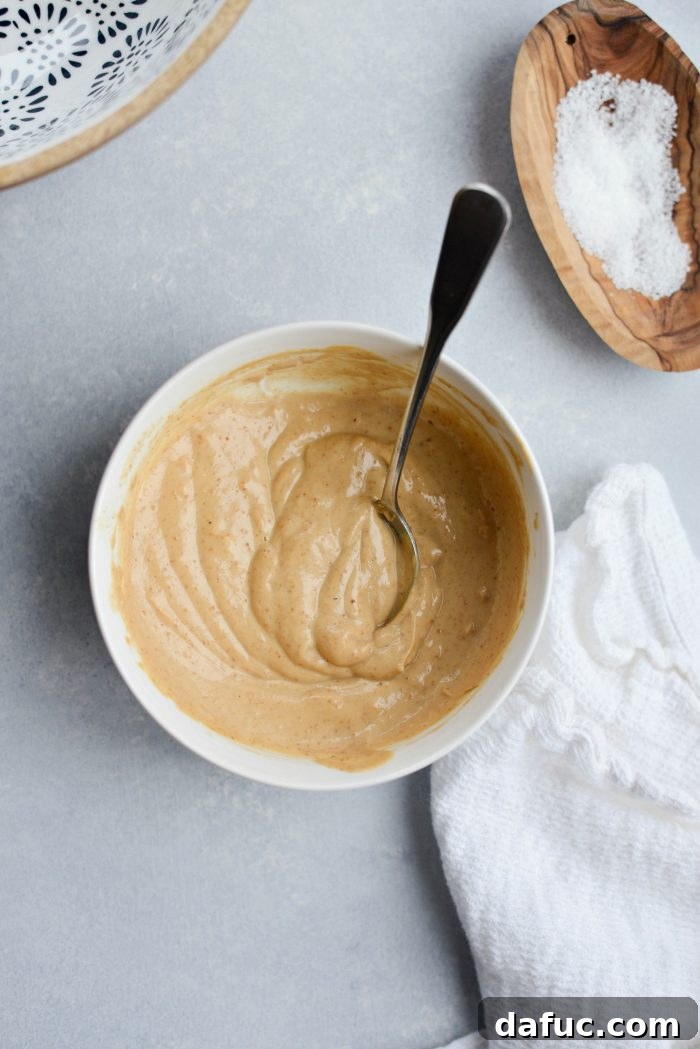 Close-up shot of creamy cashew dressing in a small glass jar, garnished with a lime slice